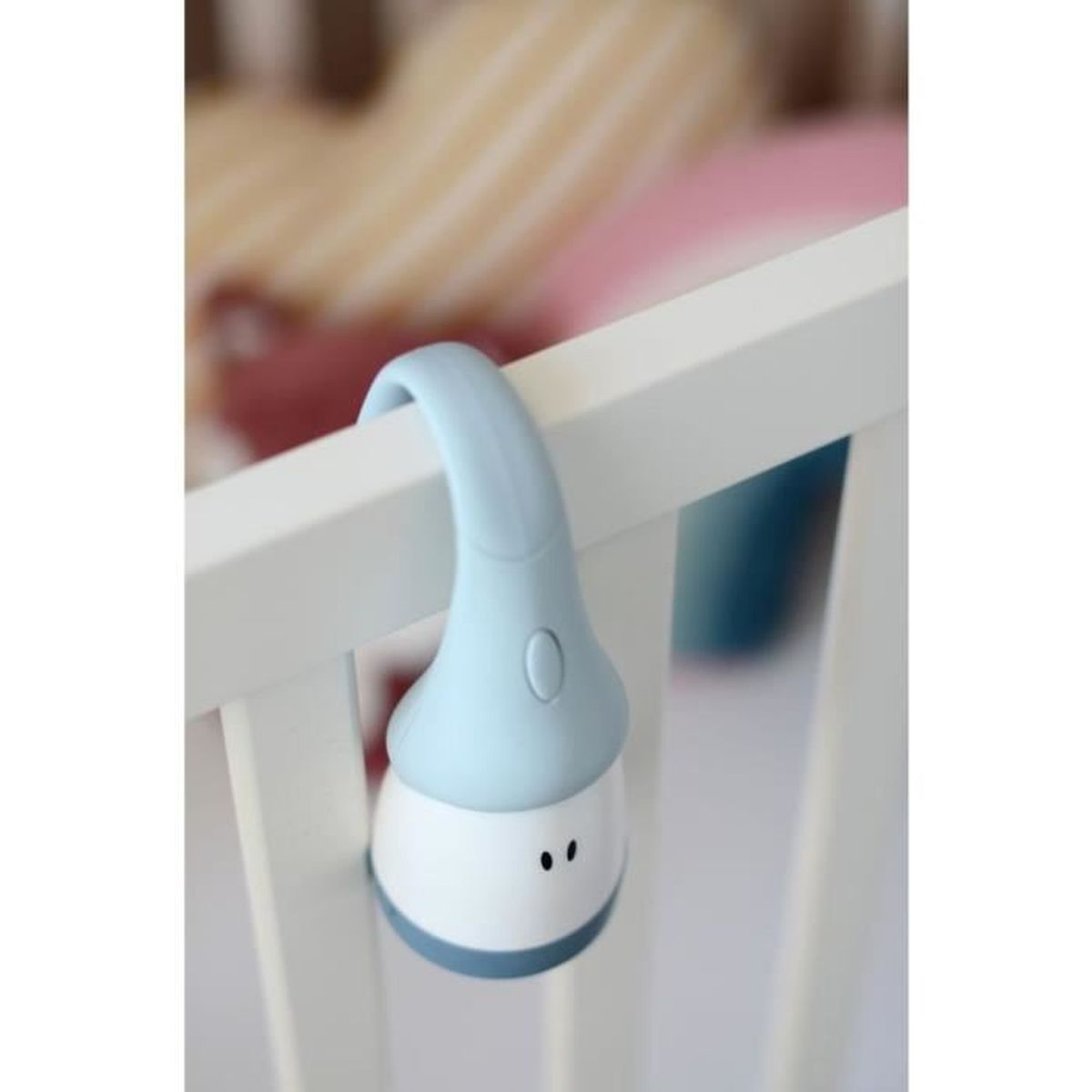 Ein hellblaues Babymobile, das an einem weißen Kinderbett hängt. Das Mobile hat eine runde, blaue Oberseite.