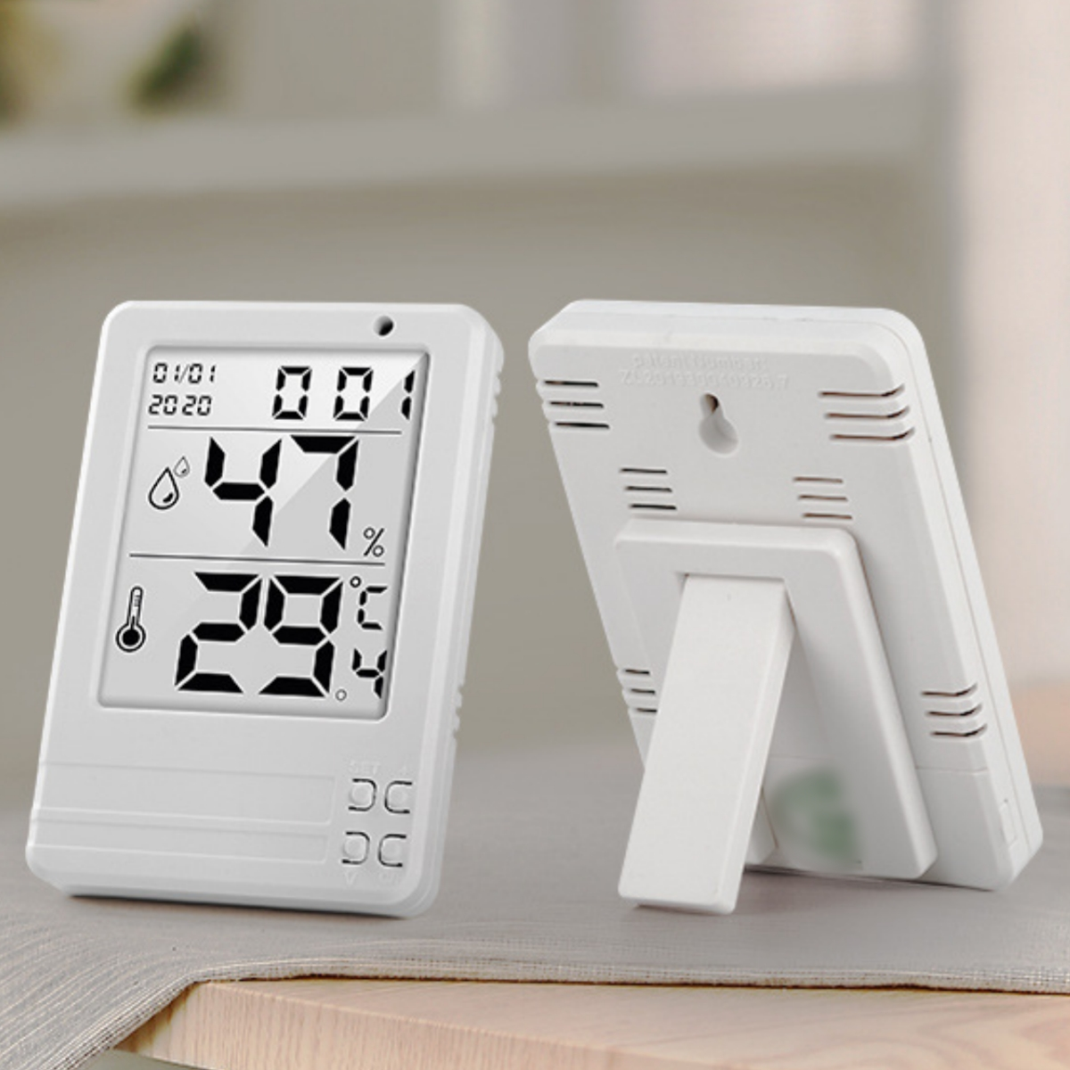 Zwei weiße digitale Thermometer, eines mit Ständer, zeigen Temperatur und Feuchtigkeit.