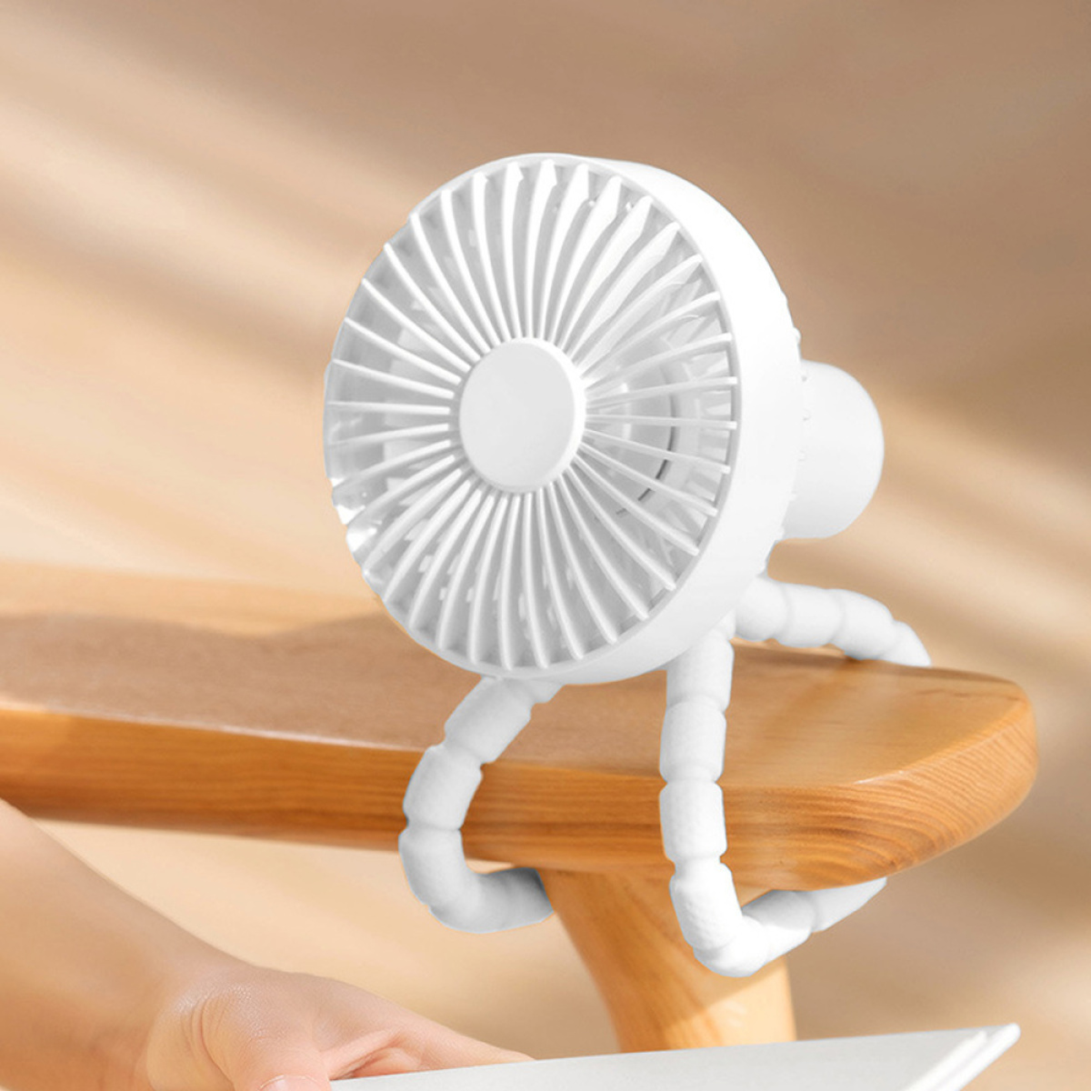 Ein weißer tragbarer Ventilator mit flexiblen Beinen steht auf einer Holzoberfläche.