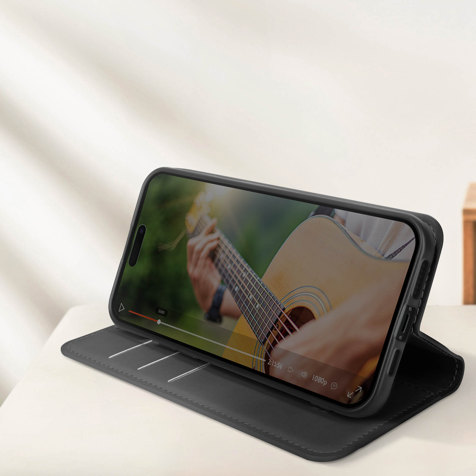 Telefono in una custodia nera, che mostra un video di chitarra su un tavolo bianco.