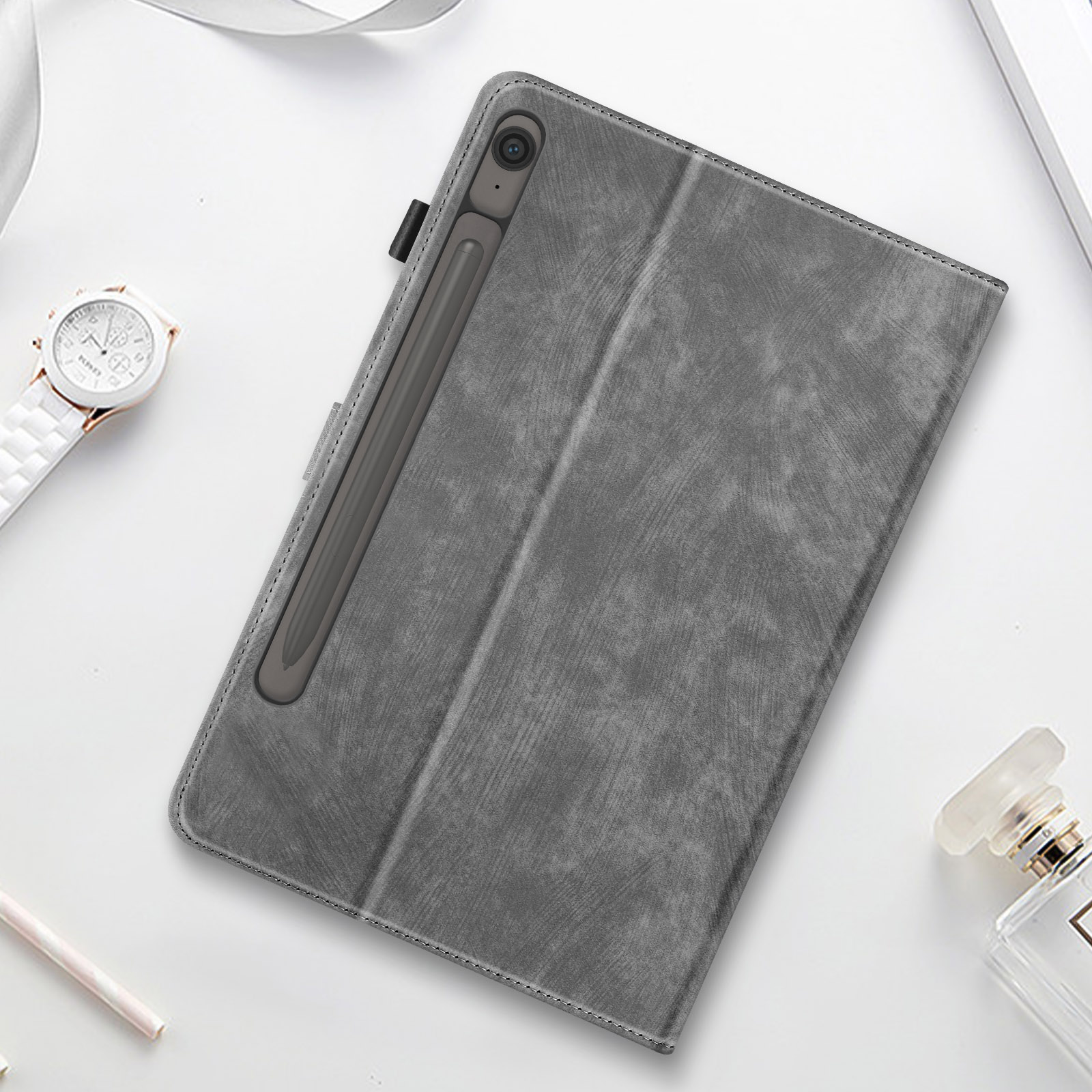 Custodia grigia per tablet con pennino e altri accessori su una superficie bianca.