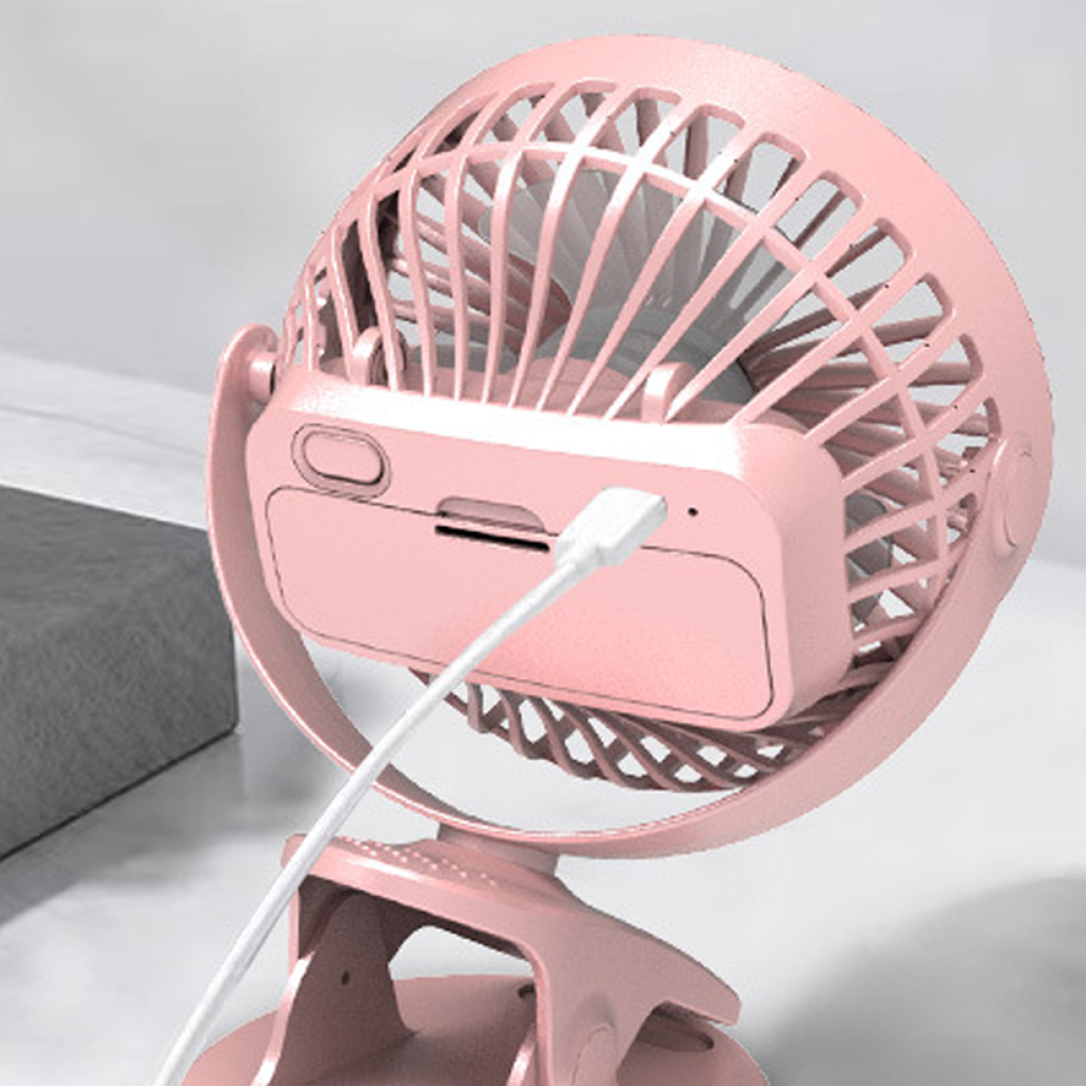 Ein rosa tragbarer Ventilator mit USB-Kabel und Clip, vor hellem Hintergrund.