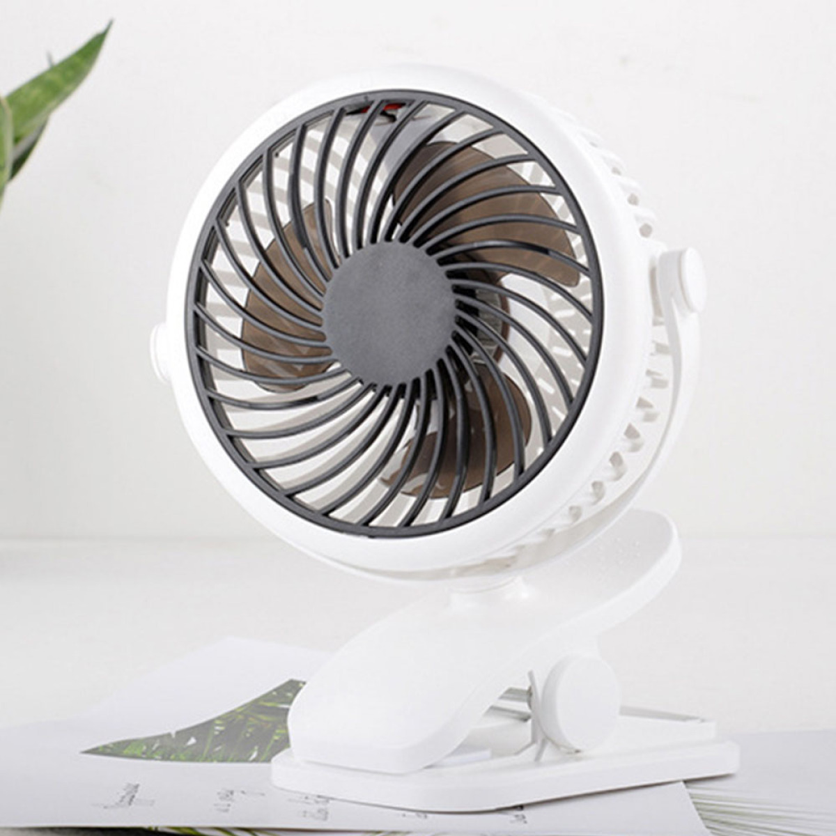 Weißer Schreibtischventilator mit schwarzen Flügeln, montiert an einem weißen Clip. Der Hintergrund ist weiß.