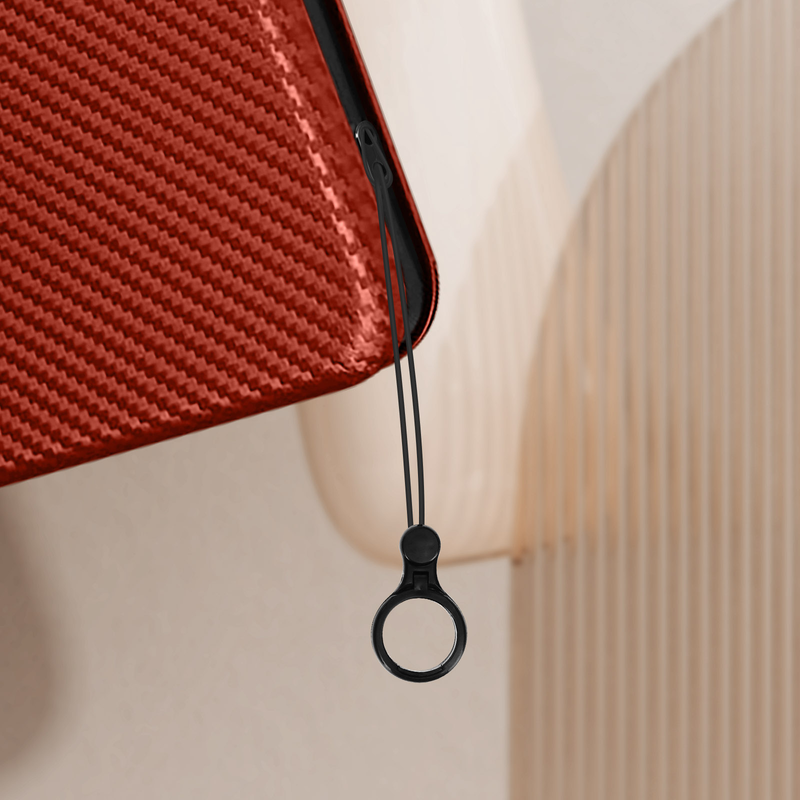 Primo piano di un tessuto rosso, con cerniera nera e linguetta. Sfondo beige e crema.