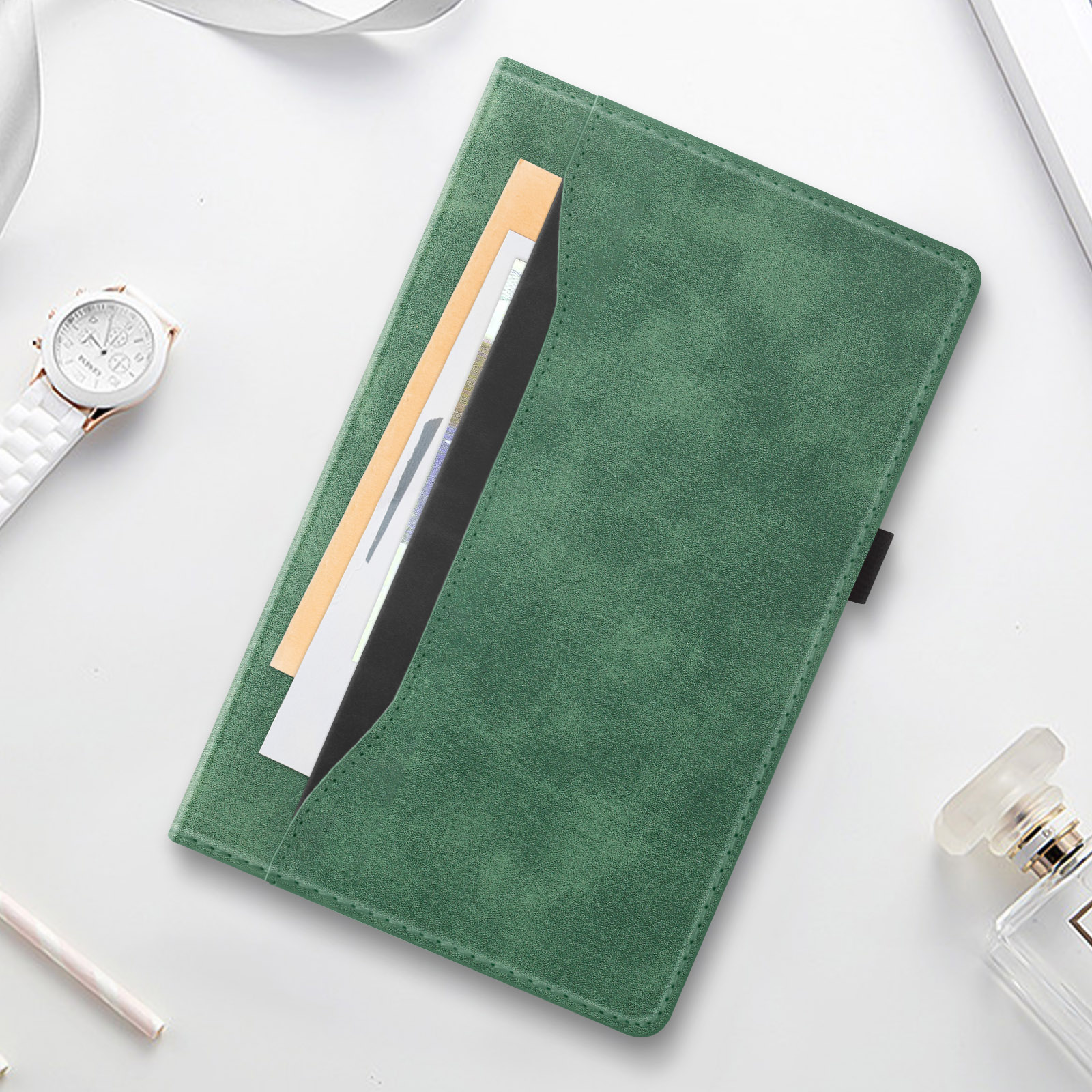 Una custodia per tablet in pelle verde con una tasca contenente documenti, un orologio e profumo.