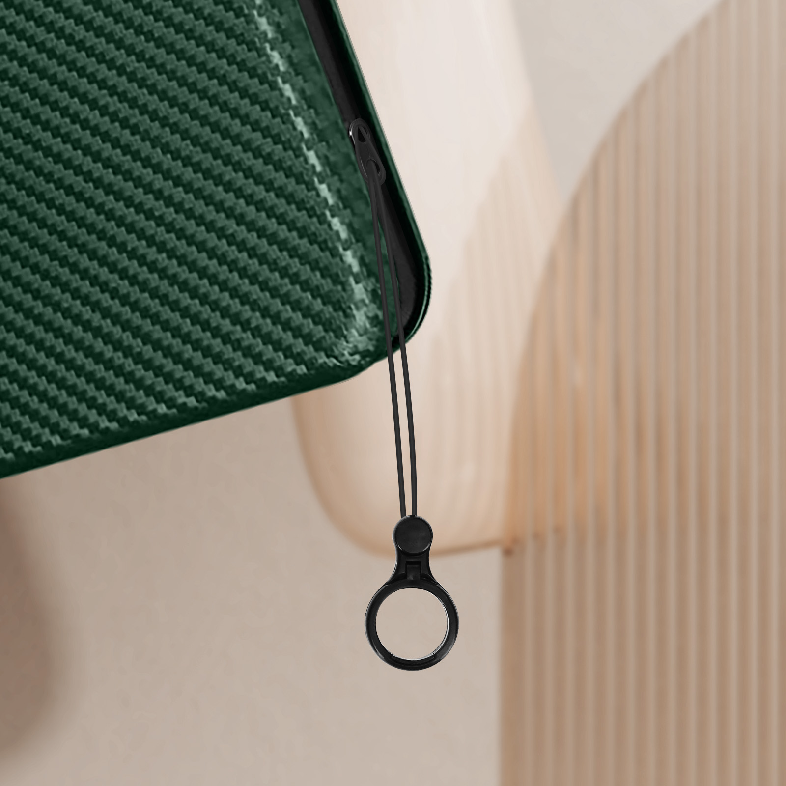 Una custodia per telefono verde, strutturata, con un cinturino e un anello neri. Lo sfondo è beige.