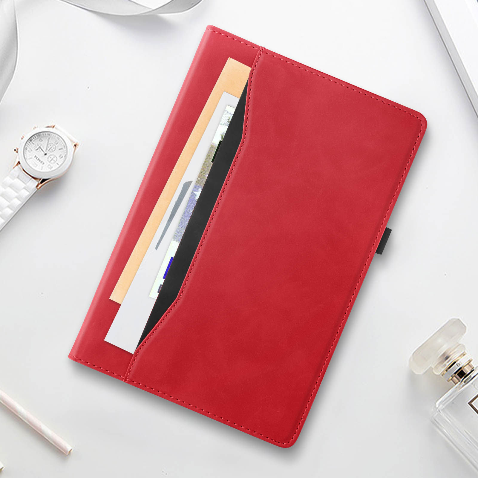Una custodia per tablet in pelle rossa con una tasca contenente documenti, un orologio e profumo.