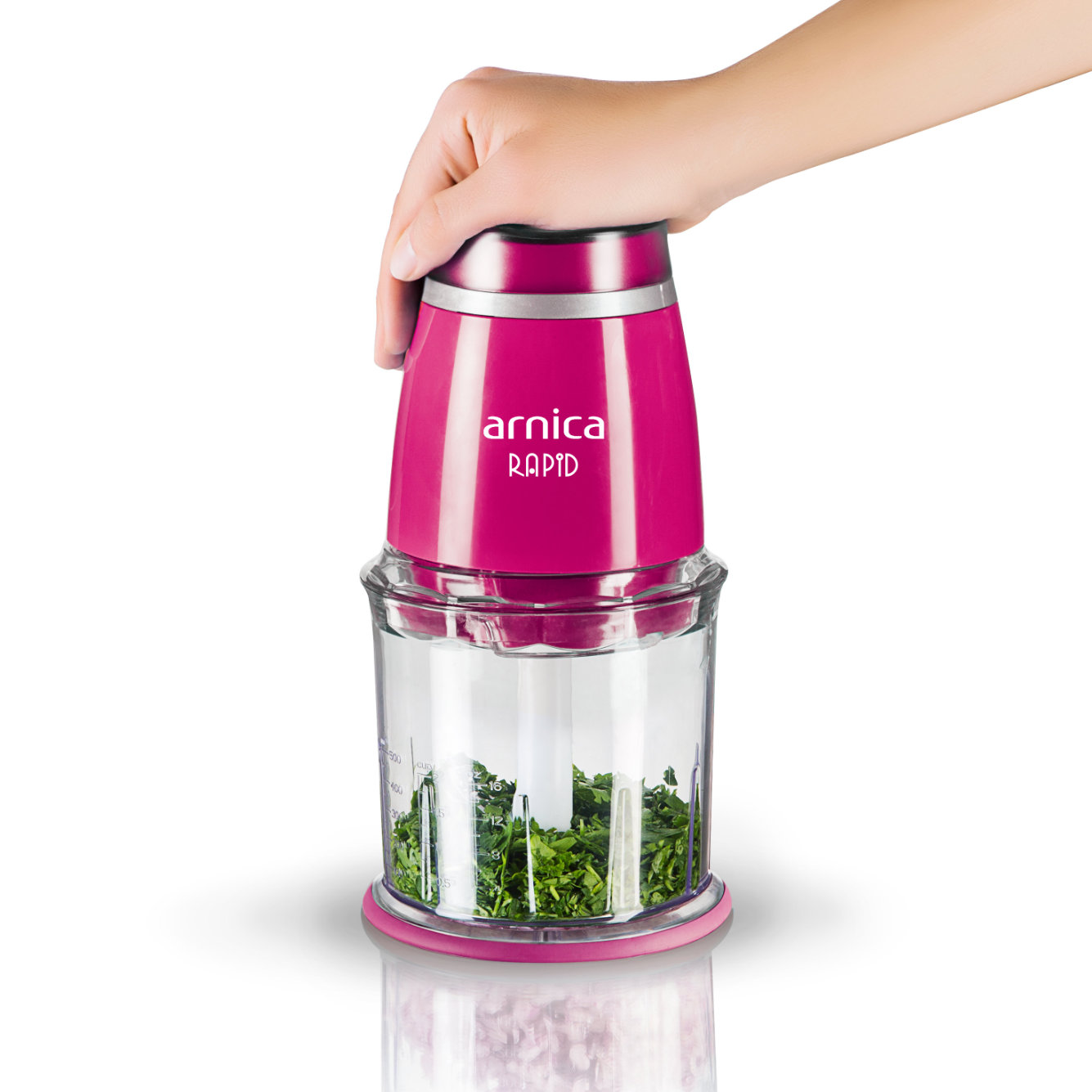 Eine Hand hält einen rosa und transparenten Zerkleinerer mit gehackten Kräutern.