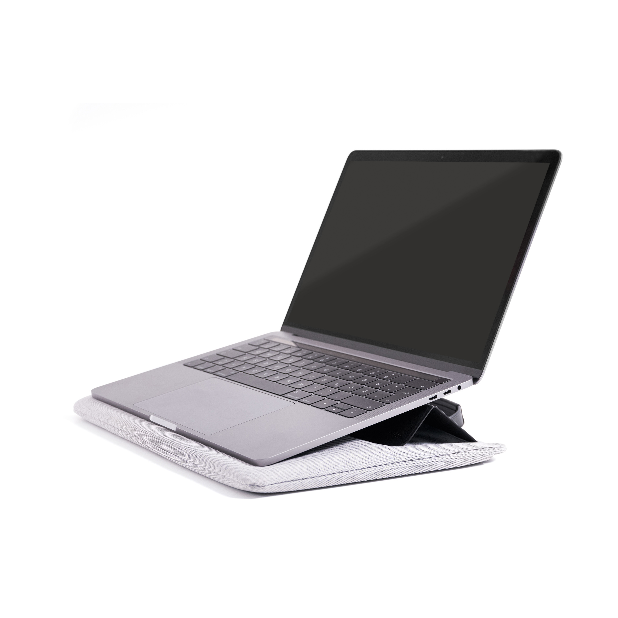 Laptop auf einem grauen Kissen, angewinkelt auf weißem Hintergrund.