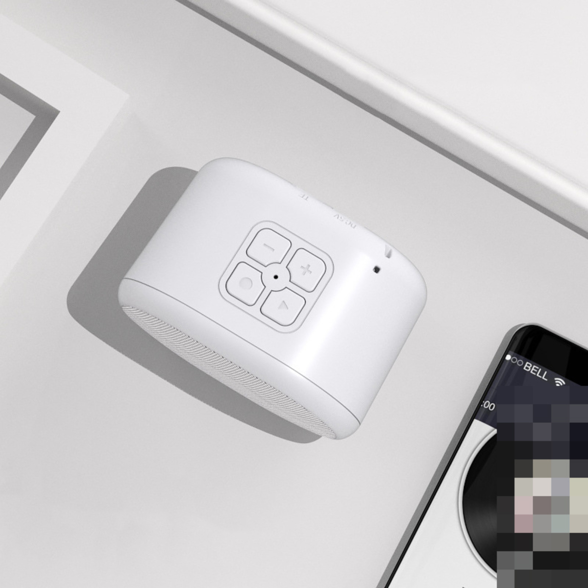 Weißer Lautsprecher mit Knöpfen, neben einem Telefon mit Musik-App.