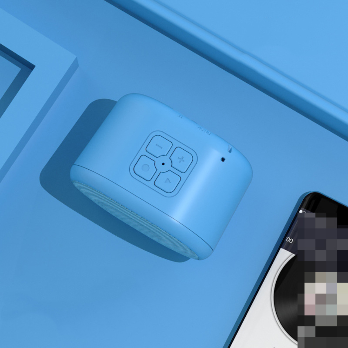 Blauer Lautsprecher mit Bedienelementen oben und einem Telefon daneben, auf blauer Oberfläche.