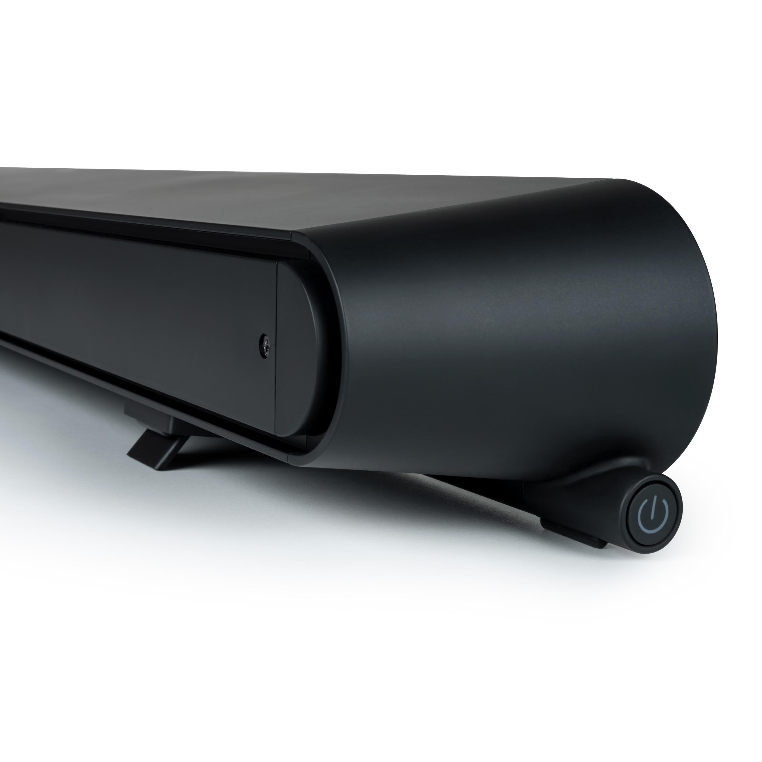 Czarny soundbar z zakrzywionym designem i przyciskiem zasilania. Na białej powierzchni.