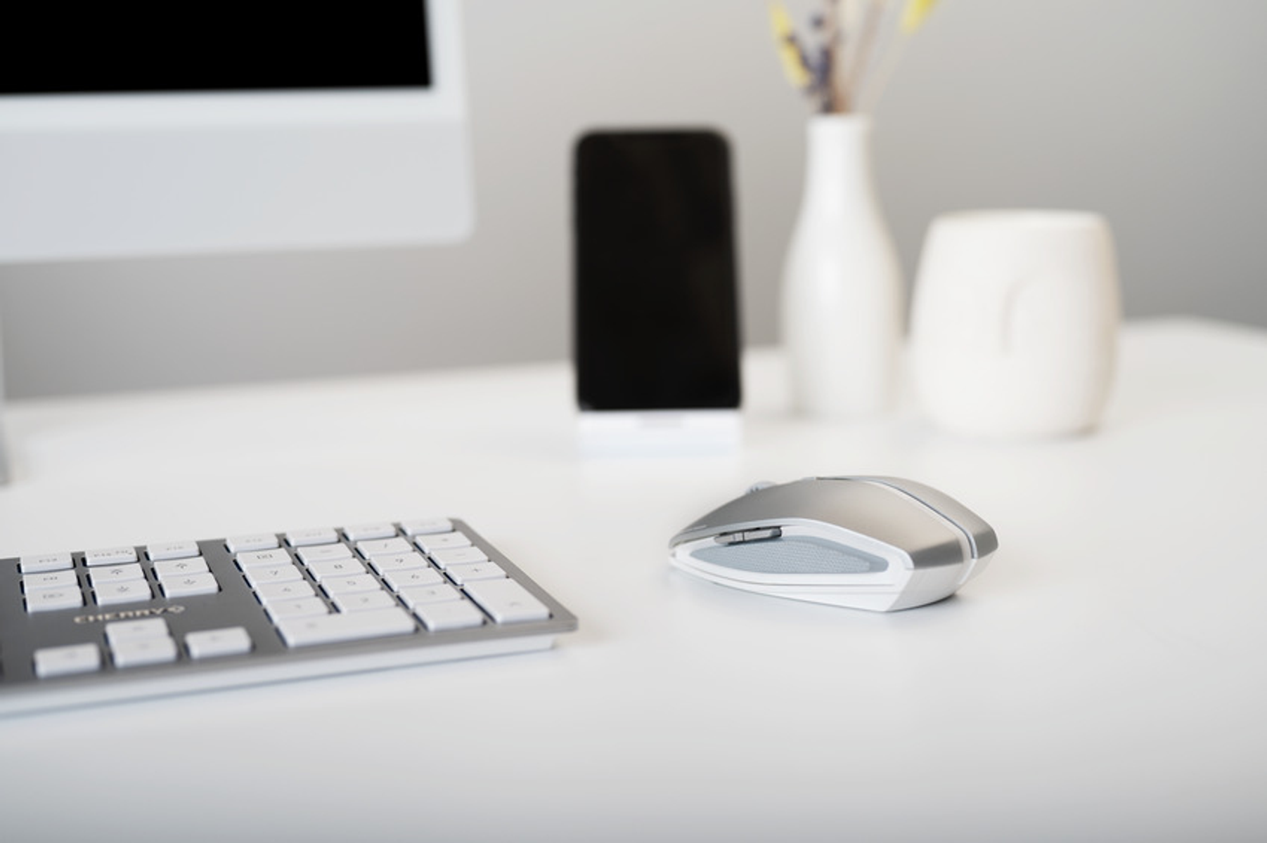 Bureau met computer, telefoon, muis en een vaas, goed georganiseerd.