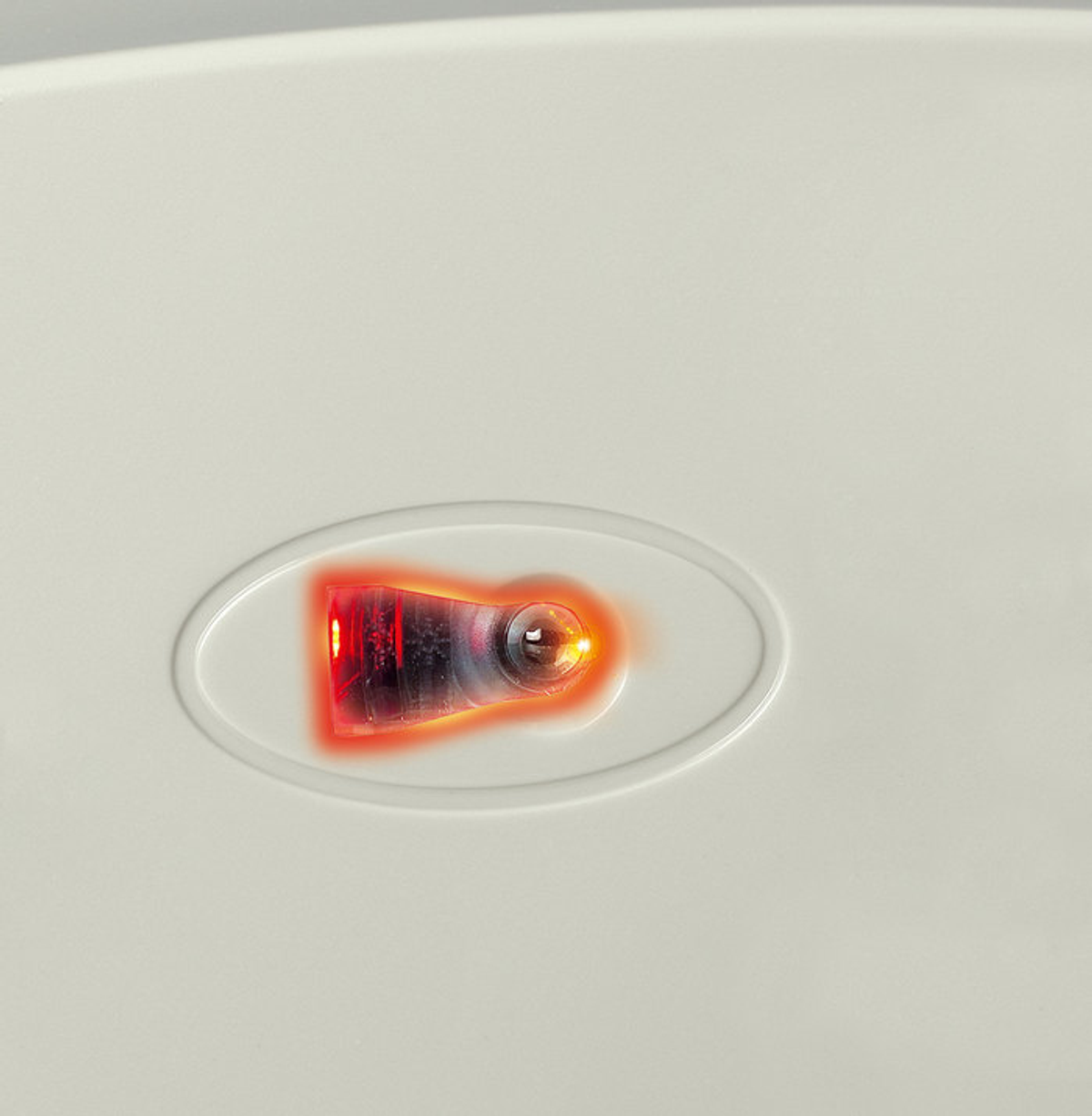 Close-up of a white surface with an illuminated red and orange light.