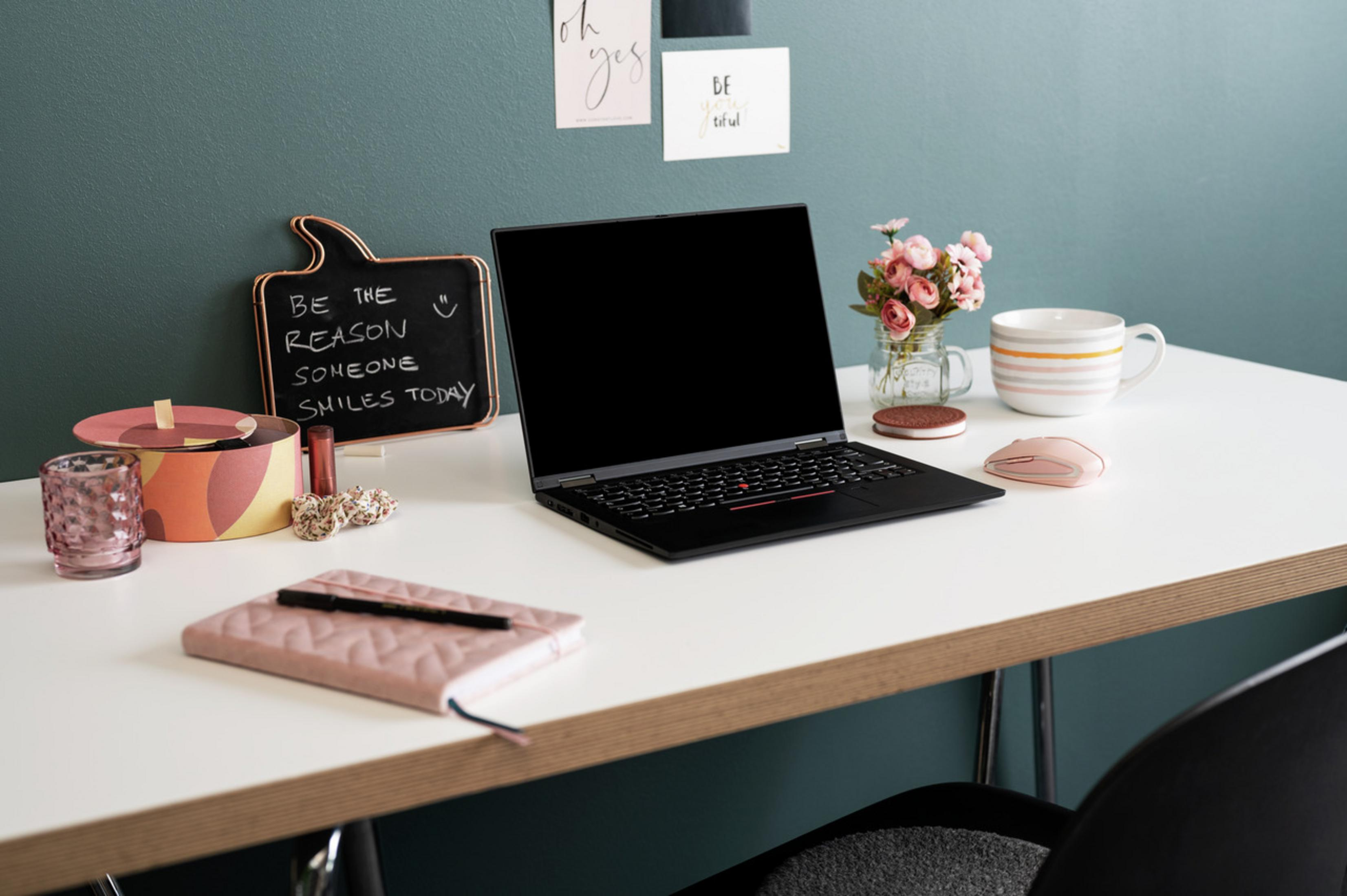 Workspace with laptop, flowers, mug, and decorations on a white desk.