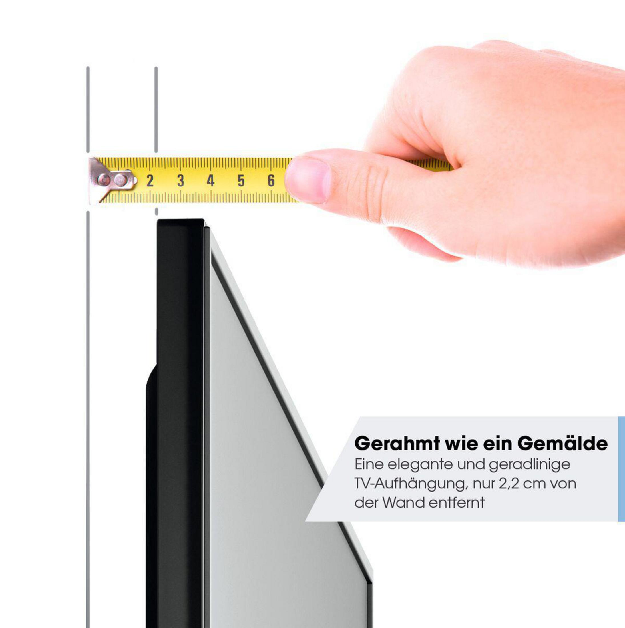 Ręka trzymająca miarkę przy boku czarnej ramy na białym tle.