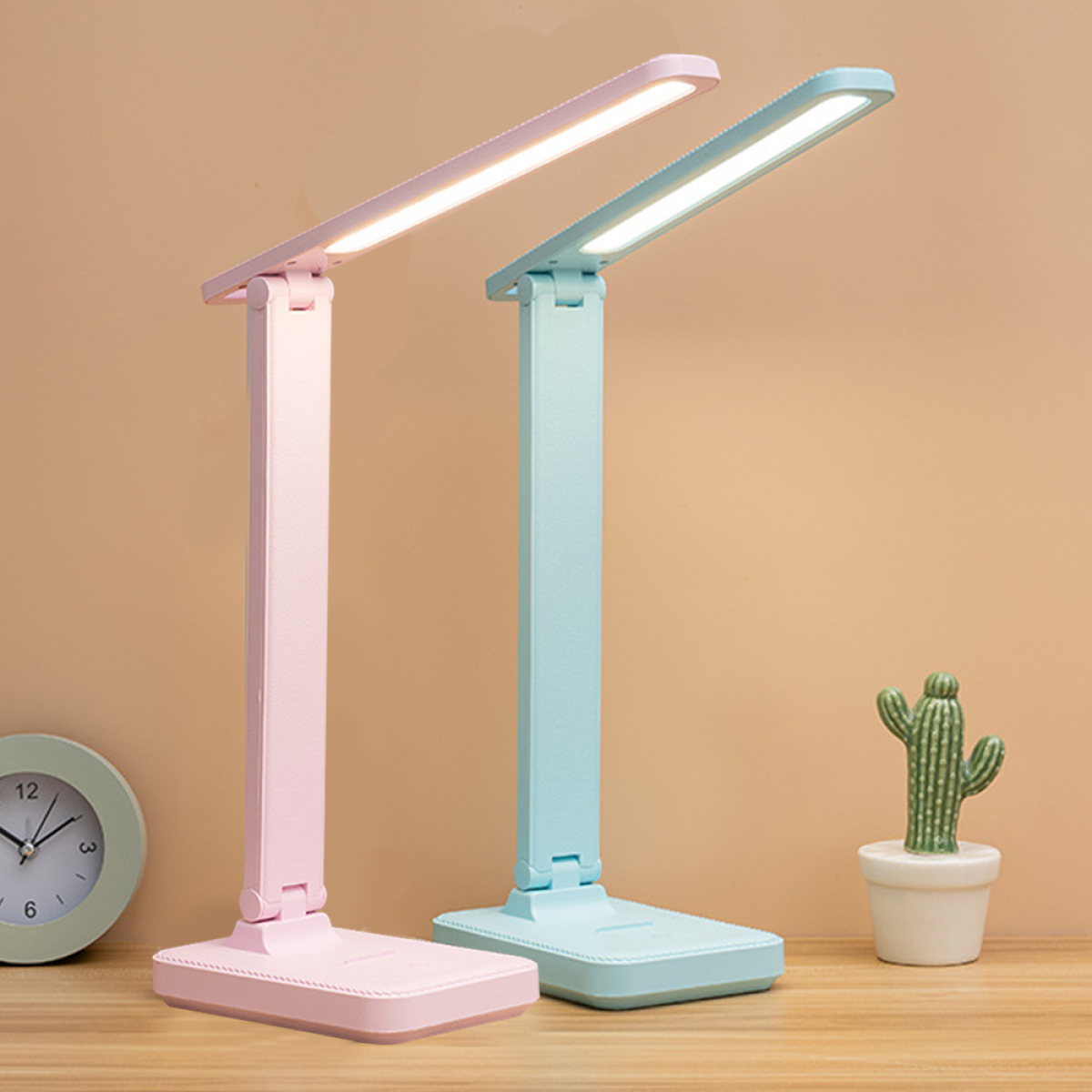 Zwei Schreibtischlampen, rosa und blau. Kaktus und Uhr im Hintergrund.