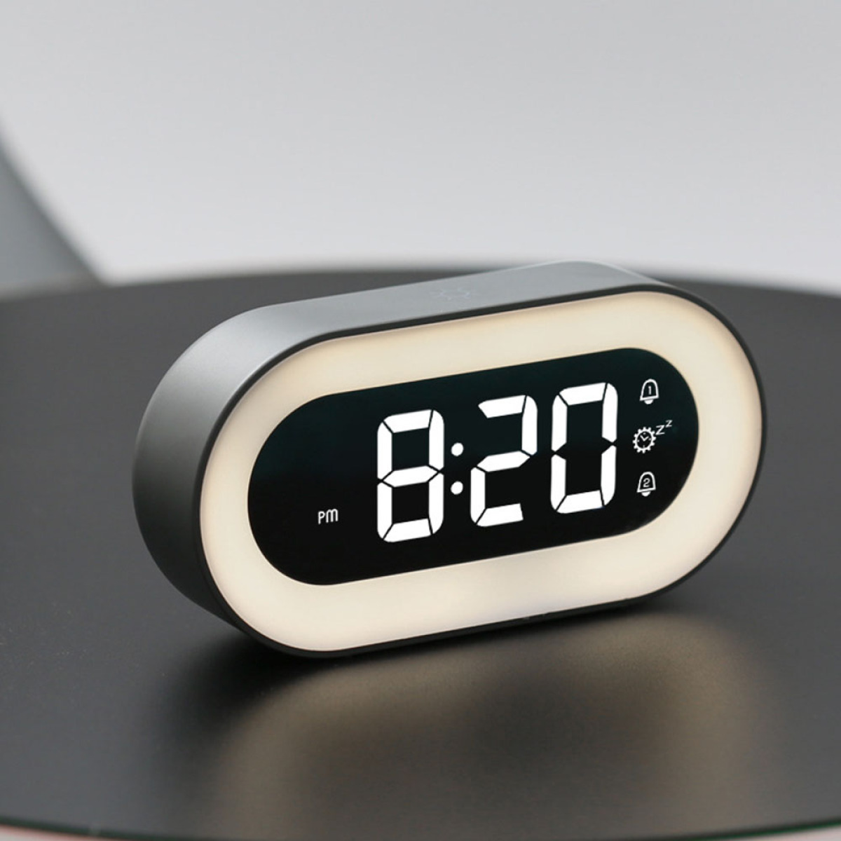 Ein schwarz-grauer digitaler Wecker mit der Anzeige 20:20 Uhr, mit weißem Leuchtrahmen.