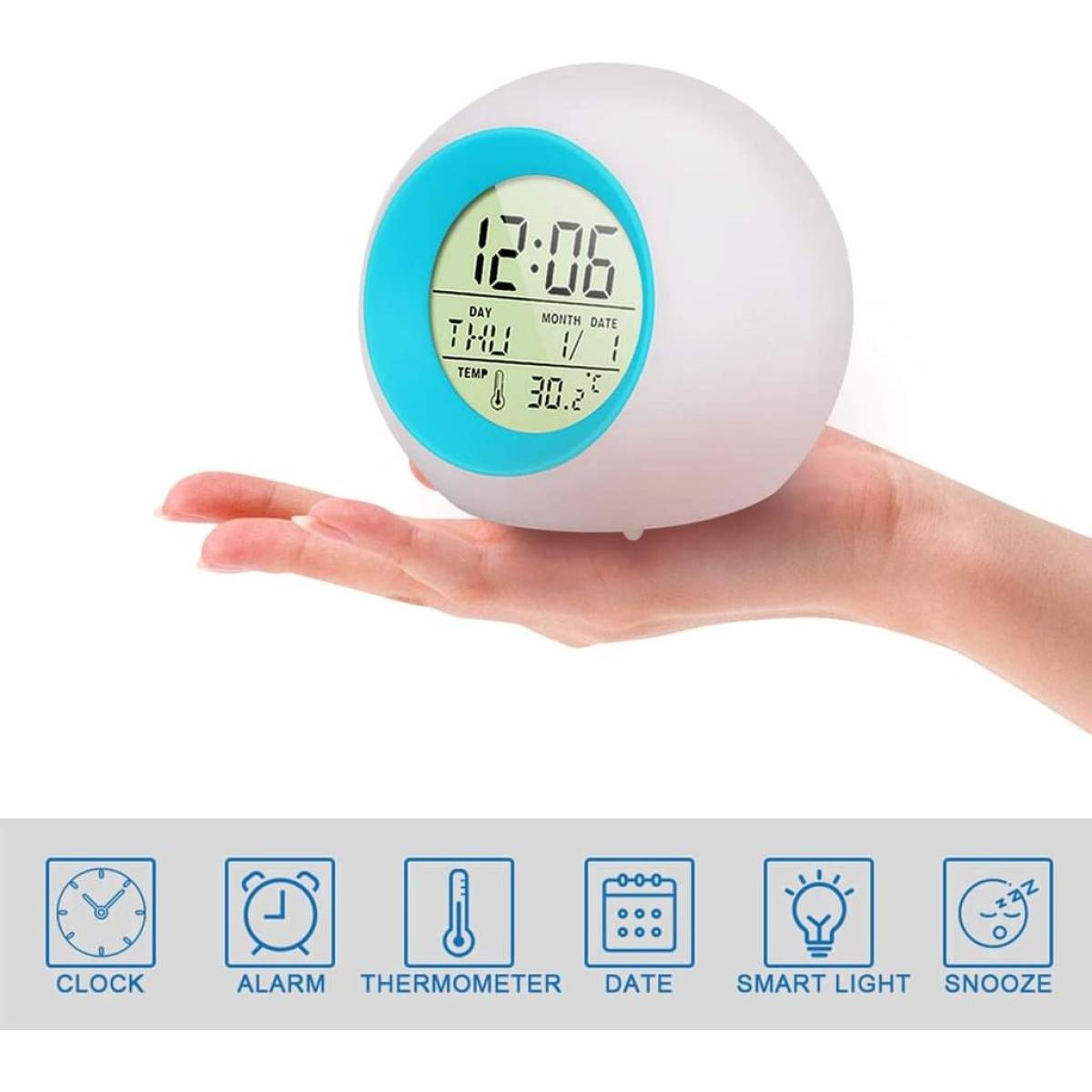 Eine weiße und blaue digitale Weckuhr wird in einer Hand gehalten. Sie zeigt die Uhrzeit, den Wochentag, das Datum und die Temperatur an.