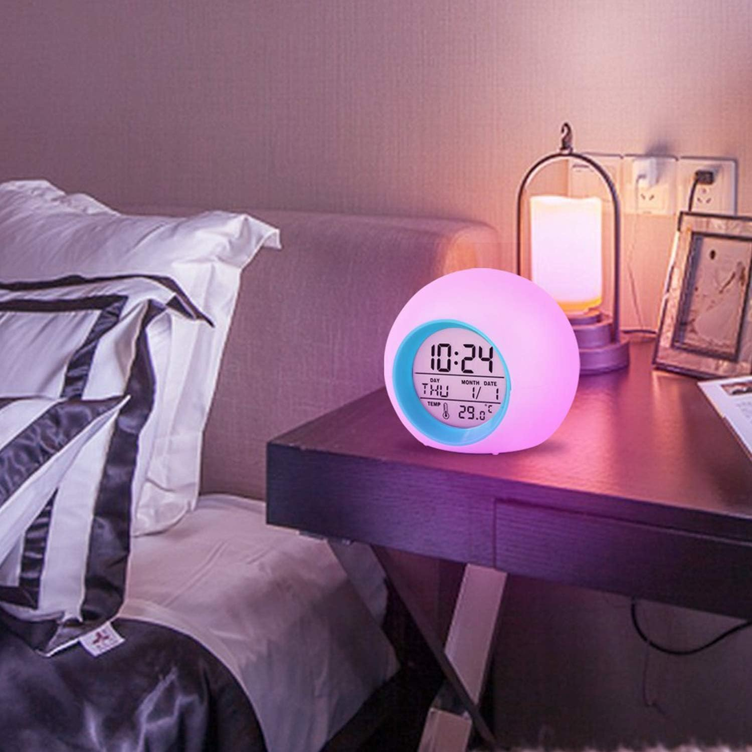 Digitaler Wecker, beleuchtet, auf einem Nachttisch. Lila und rosa Umgebungslicht.