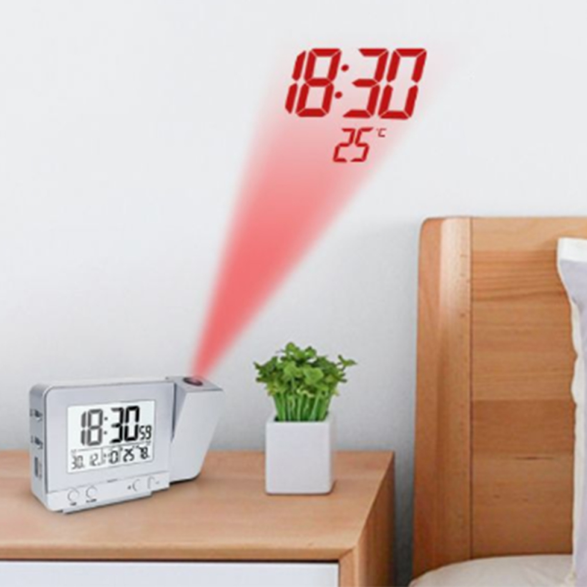 Uhr projiziert Zeit und Temperatur an die Wand. Eine Pflanze steht auf einem Nachttisch.
