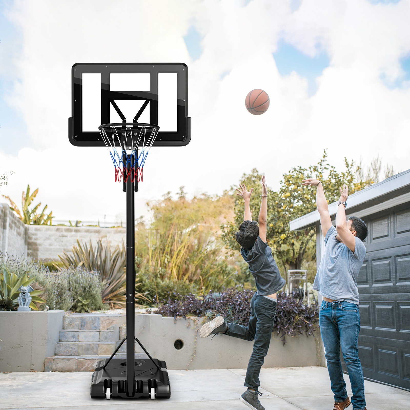 Zwei Jungen spielen Basketball. Einer schießt, der andere springt. Ein Basketballkorb ist im Hintergrund.