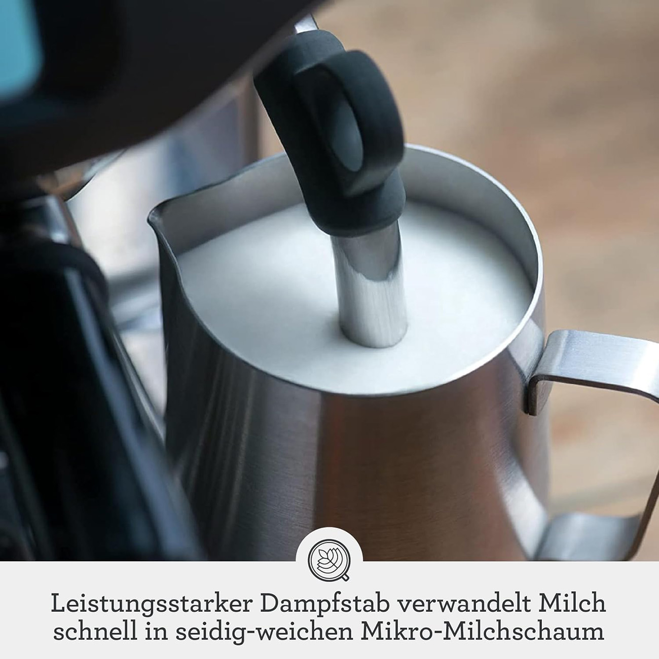Milchaufschäumkännchen aus Edelstahl mit Milch und Dampflanze. Text ist auf Deutsch.