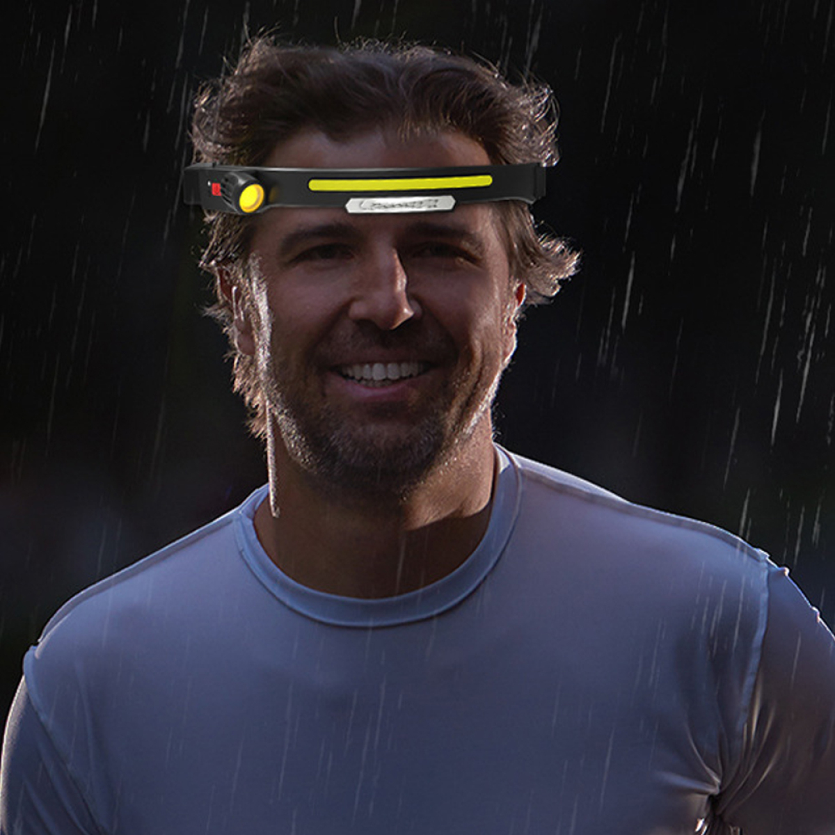 Mann mit Stirnlampe im Regen. Dunkler Hintergrund. Nahaufnahme.