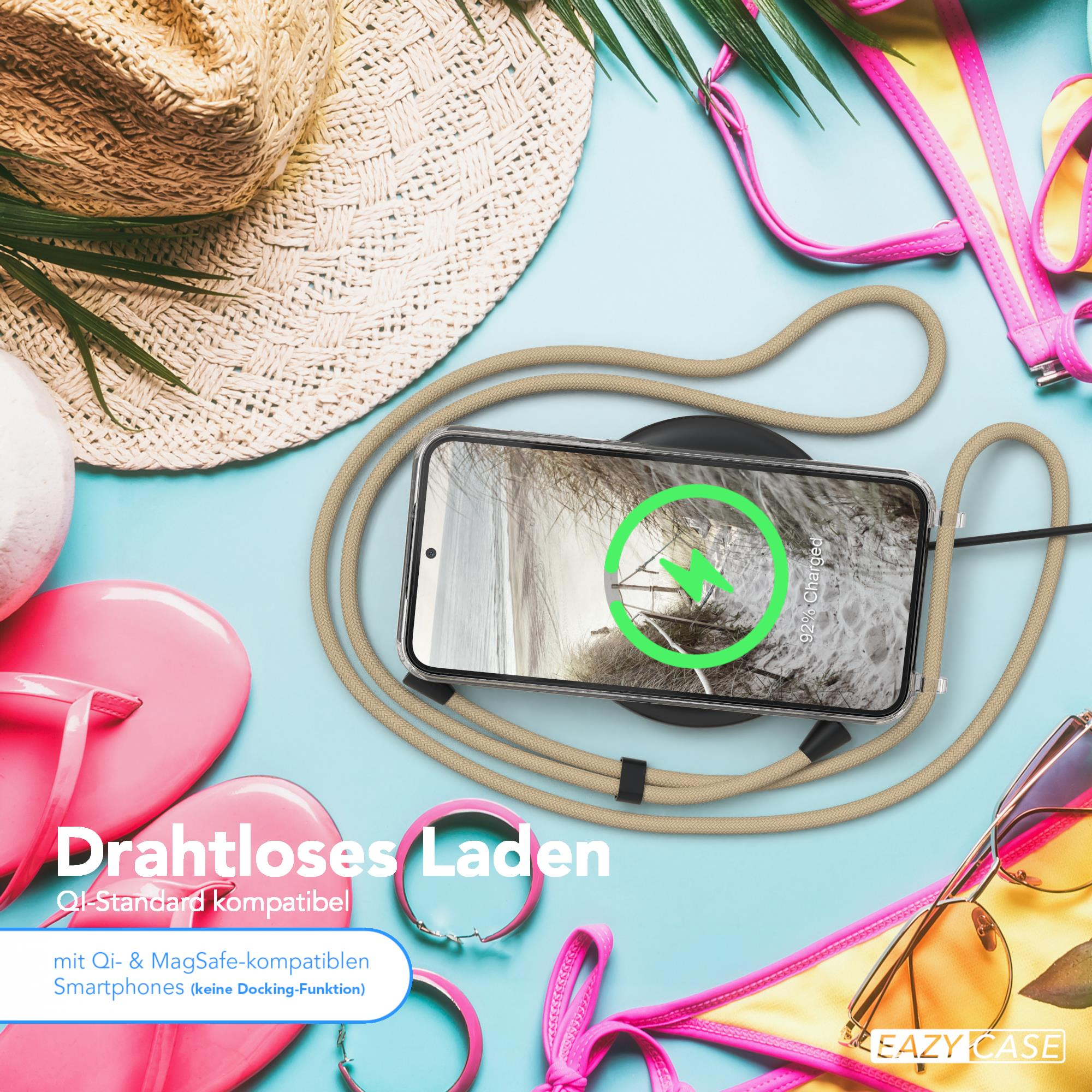 Ein Telefon wird kabellos auf einem Pad geladen. Sonnenbrille und Armband sind in der Nähe. Strandhintergrund.