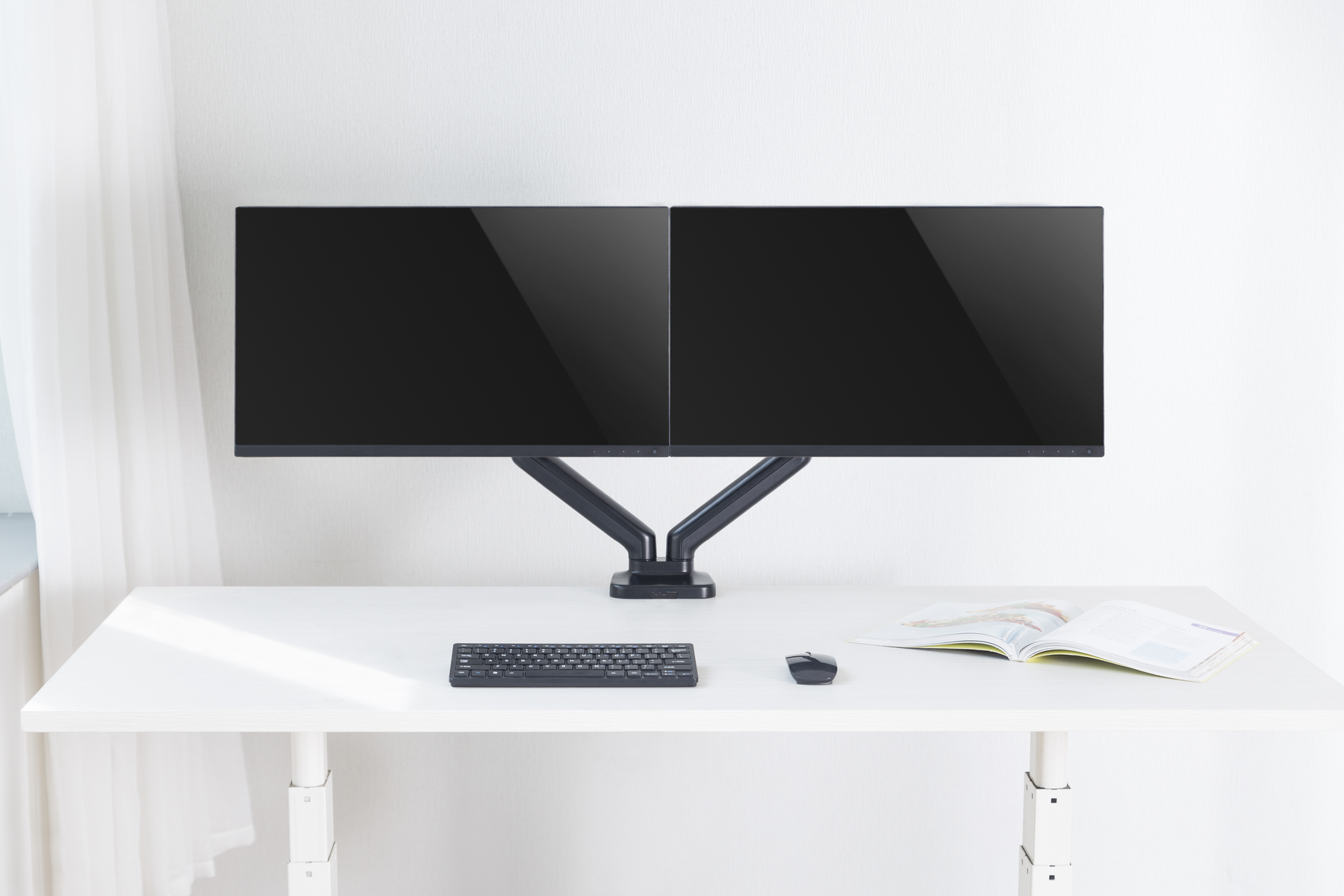 Doppel-Monitor-Setup auf weißem Schreibtisch mit Tastatur, Maus und offenem Buch.