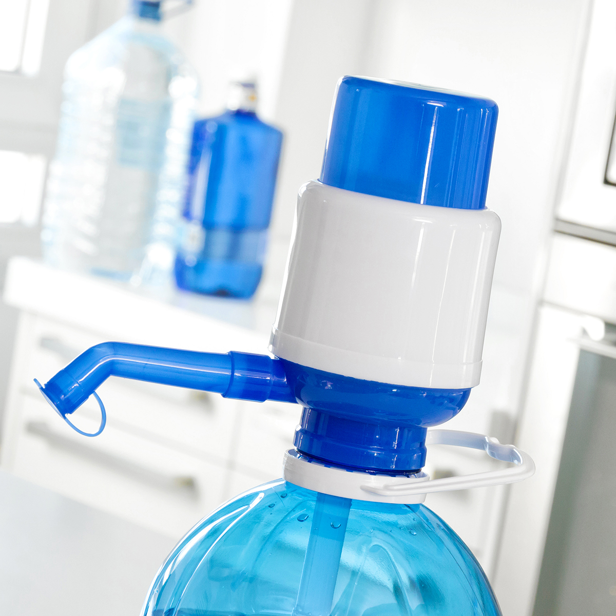 Blaue und weiße Wasserspenderpumpe mit Wasserflaschen im Hintergrund.