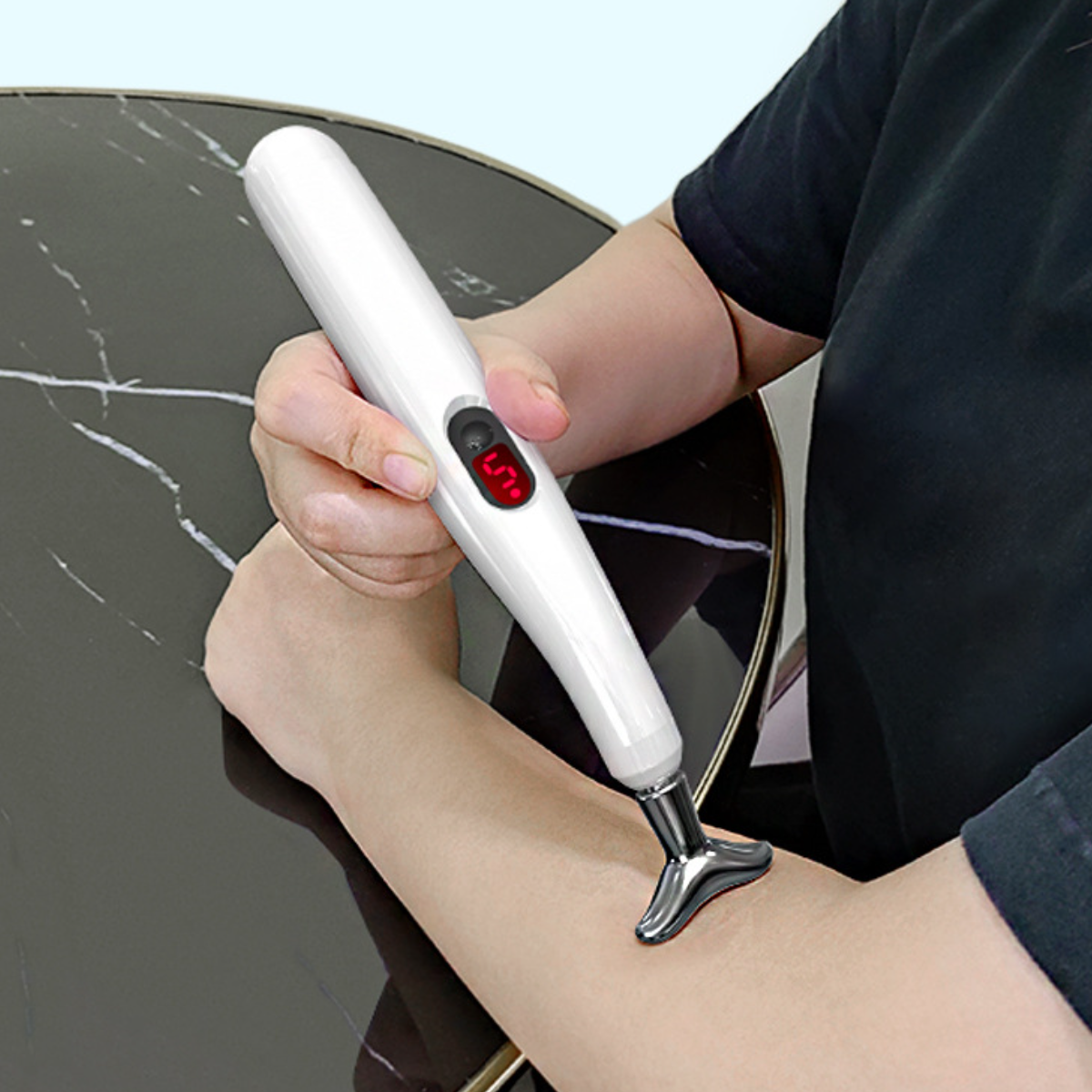Weißer Massage-Stift wird am Arm benutzt, rotes Digitaldisplay.