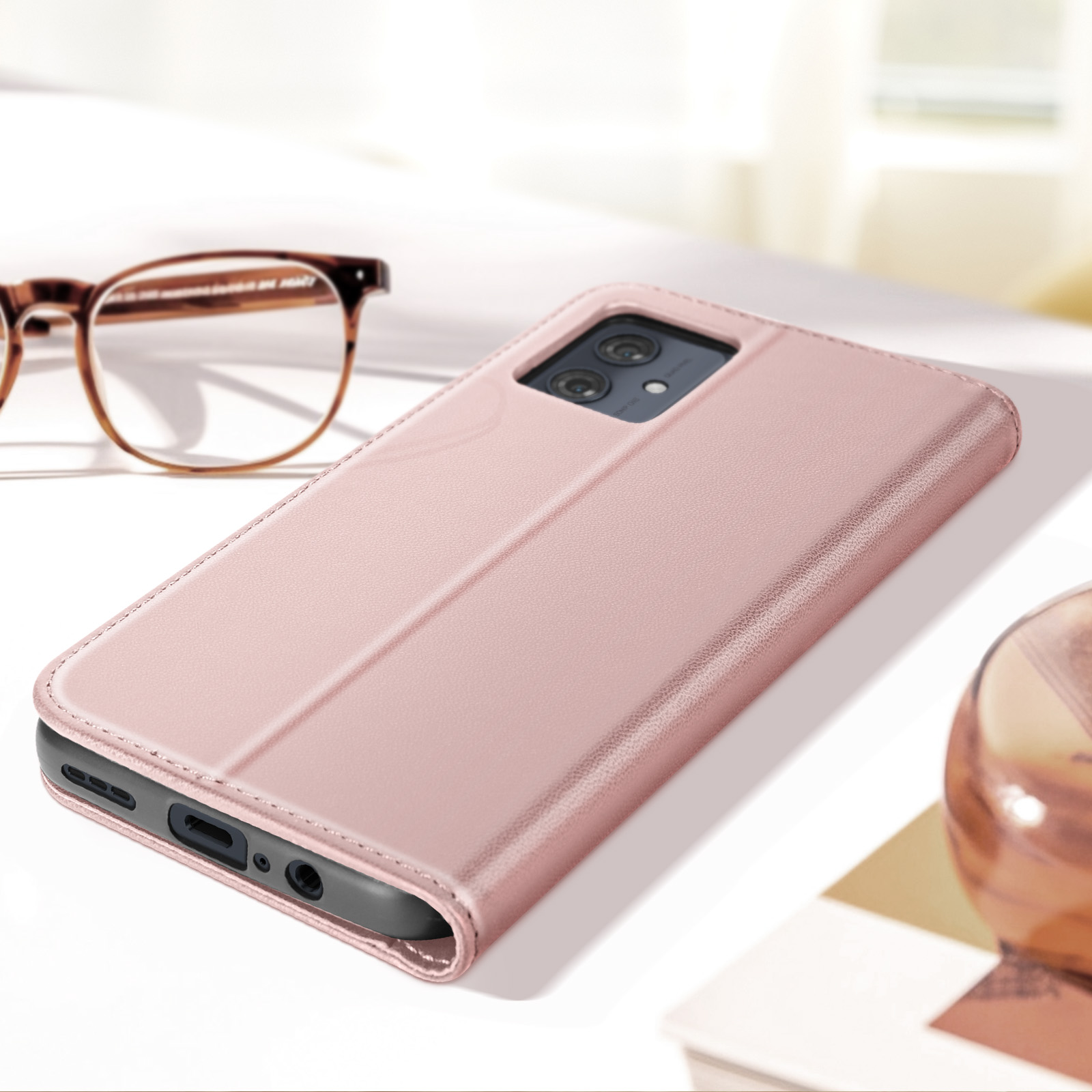 Pinke Handyhülle auf einem Tisch. Brille im Hintergrund. Die Hülle ist geöffnet.