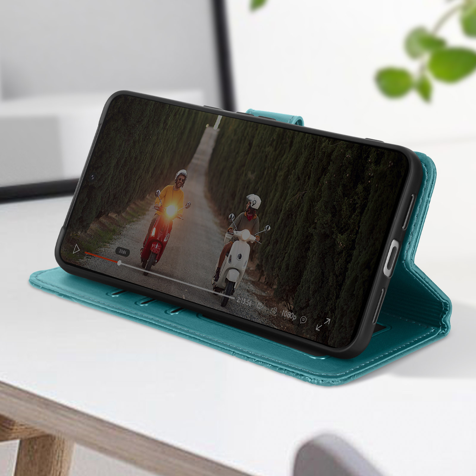 Smartphone in teal Hülle, geöffnet und zeigt Video von Rollern auf der Straße. Nahaufnahme.