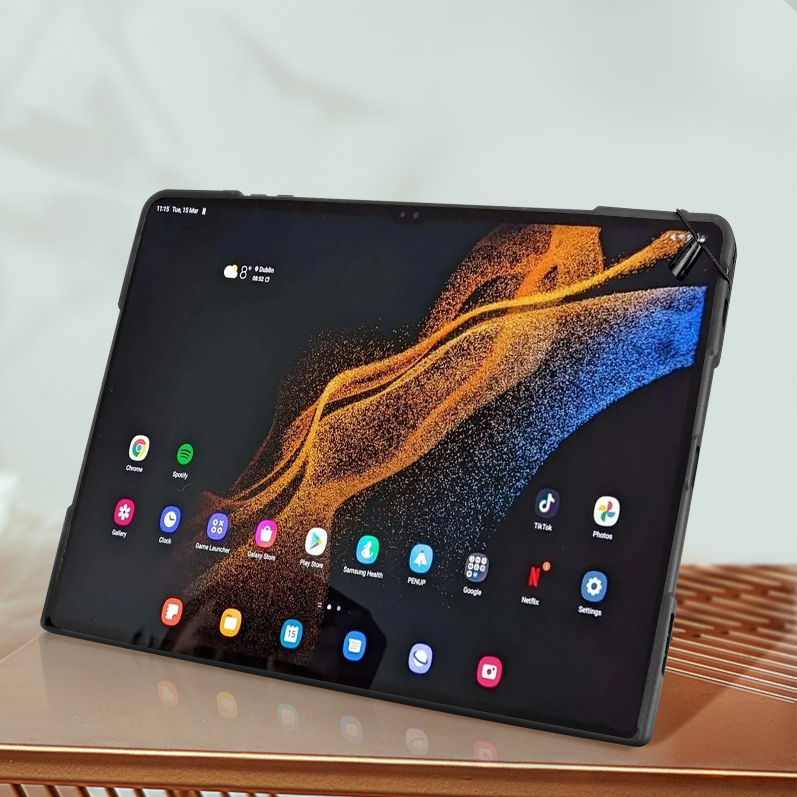 Tablet auf Ständer mit App-Symbolen, schwarzer Rahmen und goldener Hintergrund.