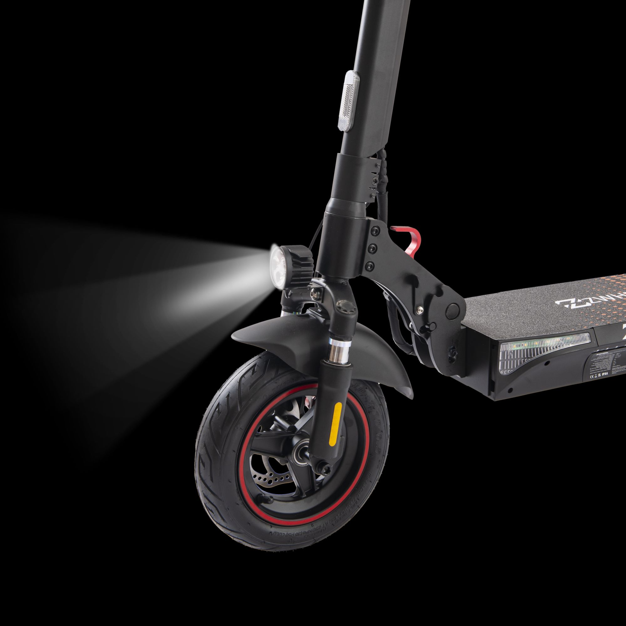 Se muestra un patinete eléctrico negro con el faro encendido, iluminando la rueda delantera.