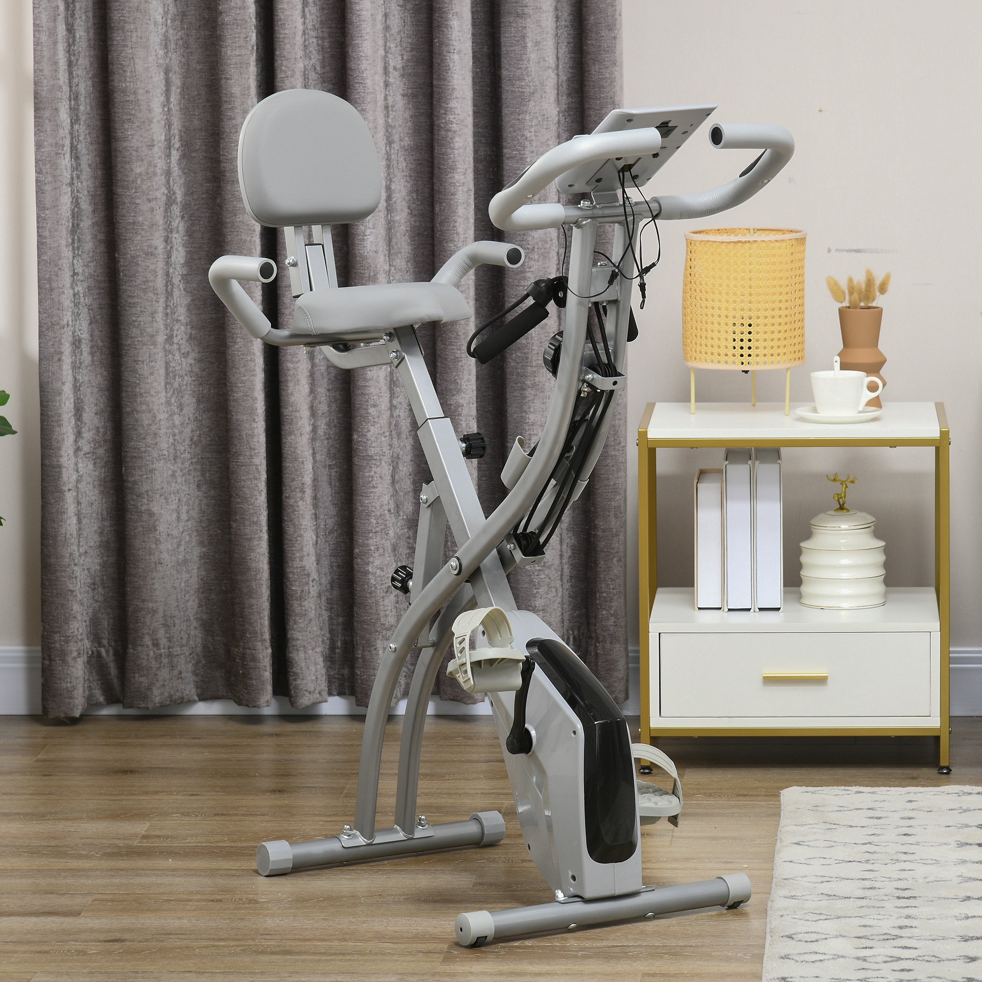 Heimtrainer mit Sitz, Griffen und Bildschirm, in einer häuslichen Umgebung.
