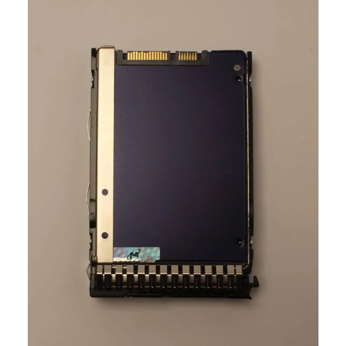 Eine dunkelblaue SSD mit Etikett und verschiedenen Anschlüssen, platziert auf einer weißen Oberfläche.