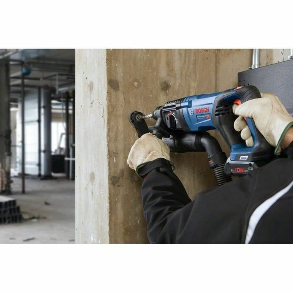 Person bohrt mit blau-schwarzem Bohrer in Betonwand.