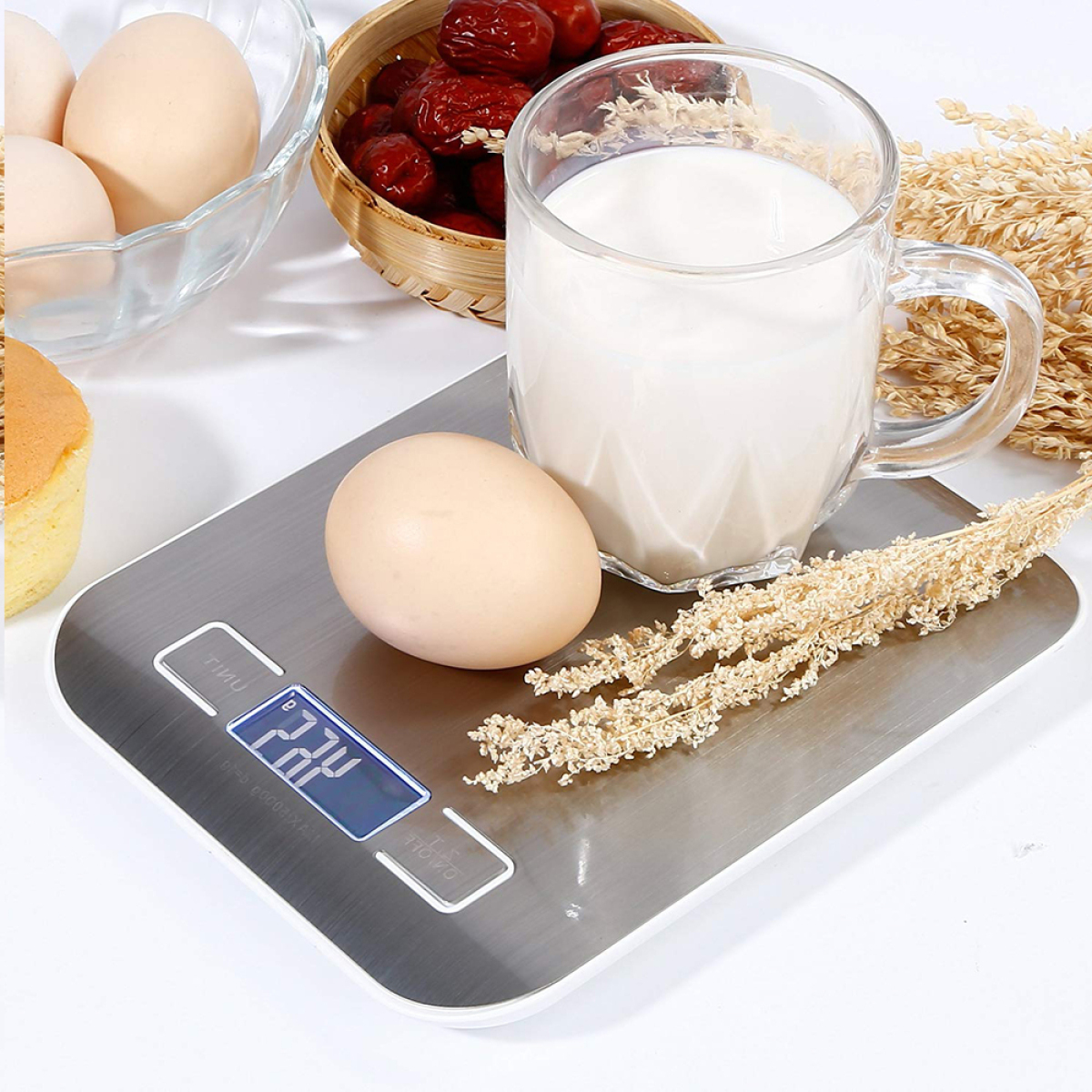 Eine Digitalwaage mit Ei, Glas Milch und Korb mit Datteln.