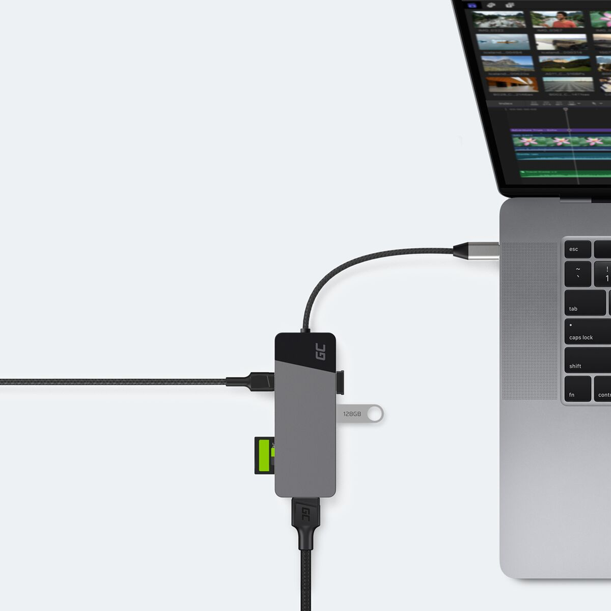 Laptop, der mit einem grauen USB-Hub mit mehreren Anschlüssen und einem eingesteckten USB-Laufwerk verbunden ist.