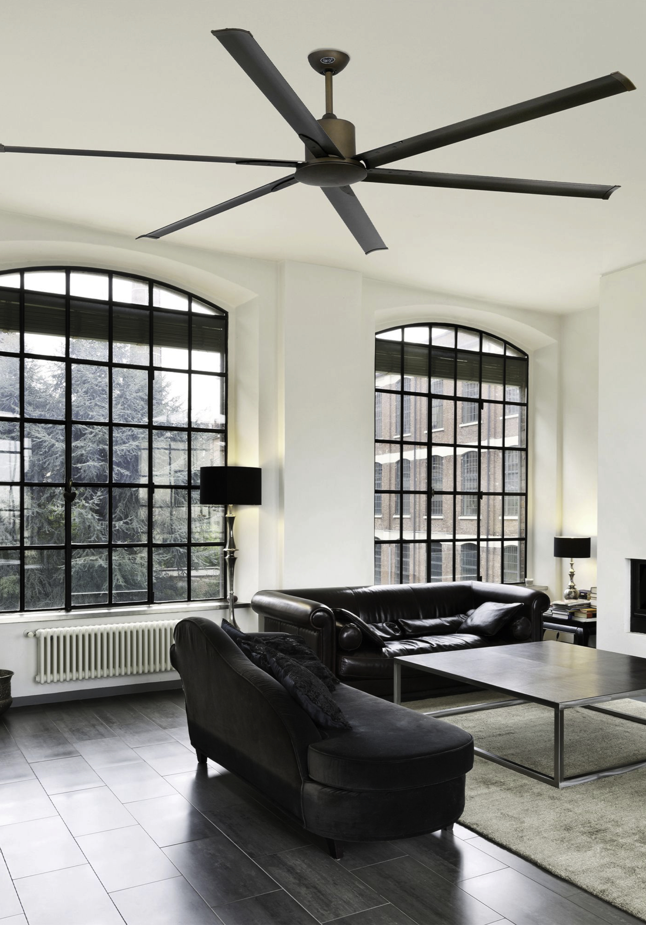 Soggiorno con ampie finestre, ventilatore a soffitto, divano in pelle e chaise longue.