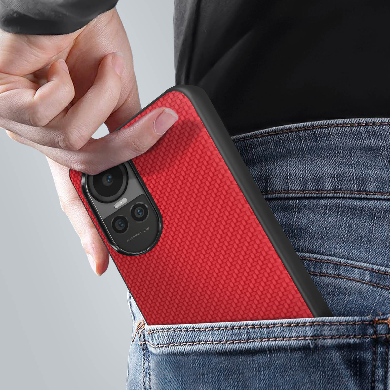 Mano che mette un telefono rosso in una tasca di jeans.