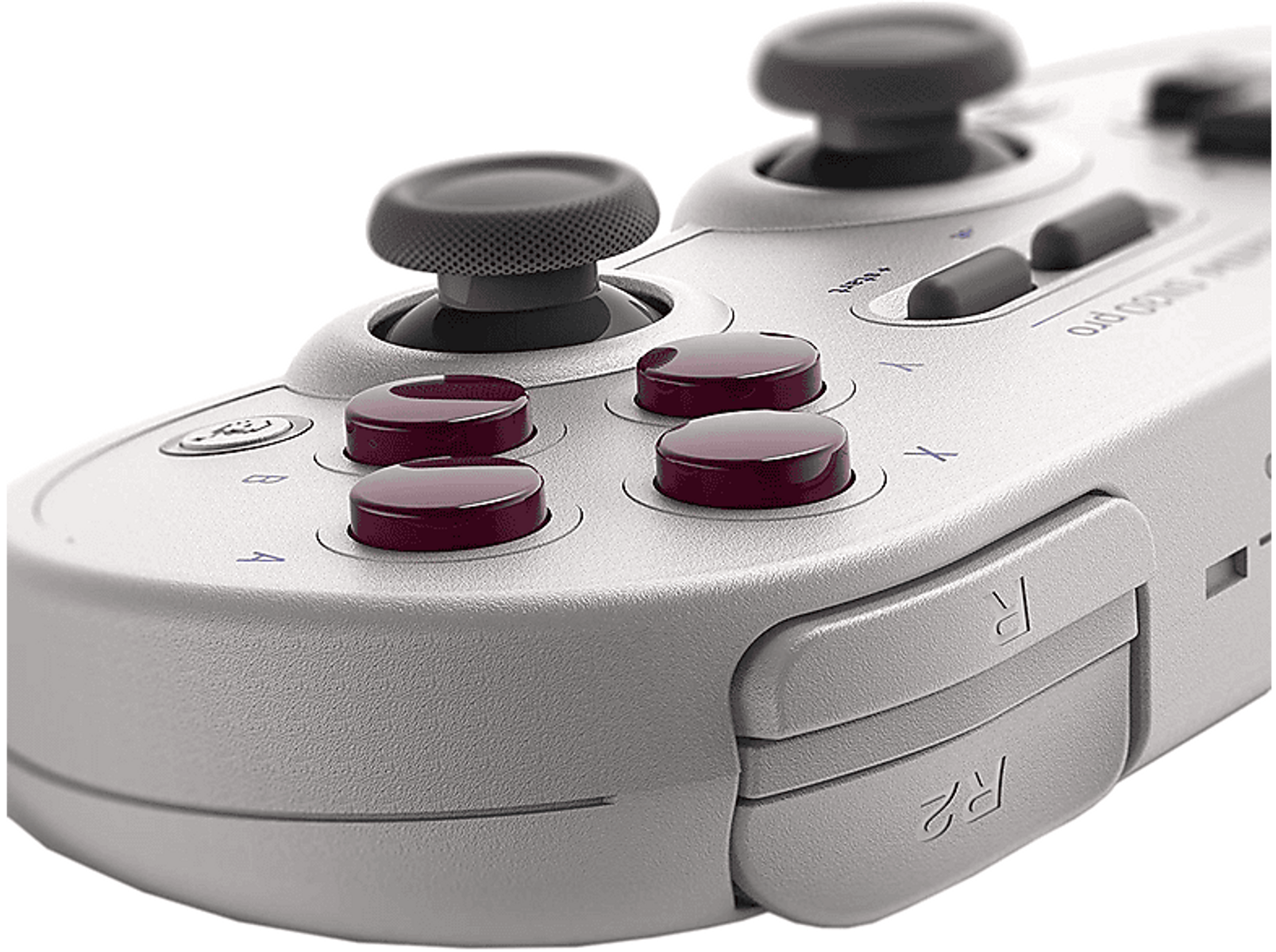 Zbliżenie szarego kontrolera do gier. Ma czerwone przyciski, czarne joysticki i białe etykiety.