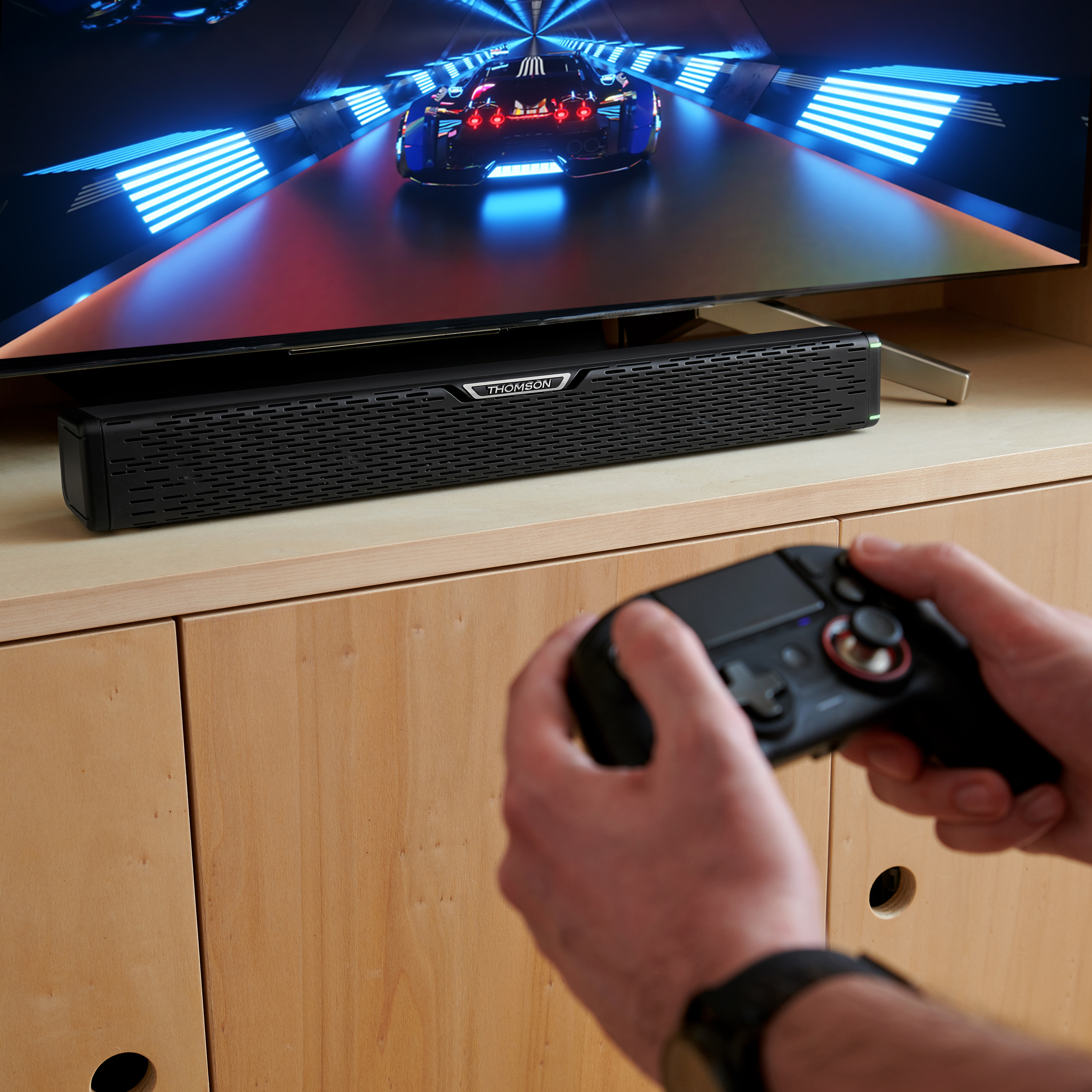 Osoba trzymająca kontroler. Jest telewizor z wyświetloną grą wyścigową.