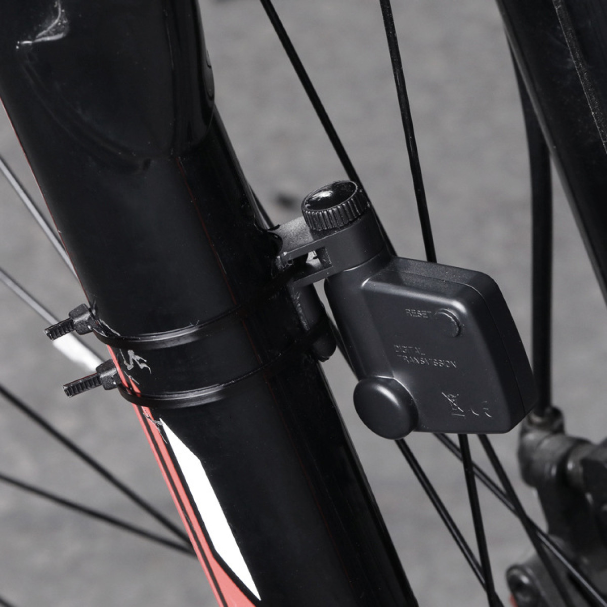 Schwarzer Fahrradcomputer an einer Fahrradgabel befestigt. Zeigt Drähte und einen Sensor.