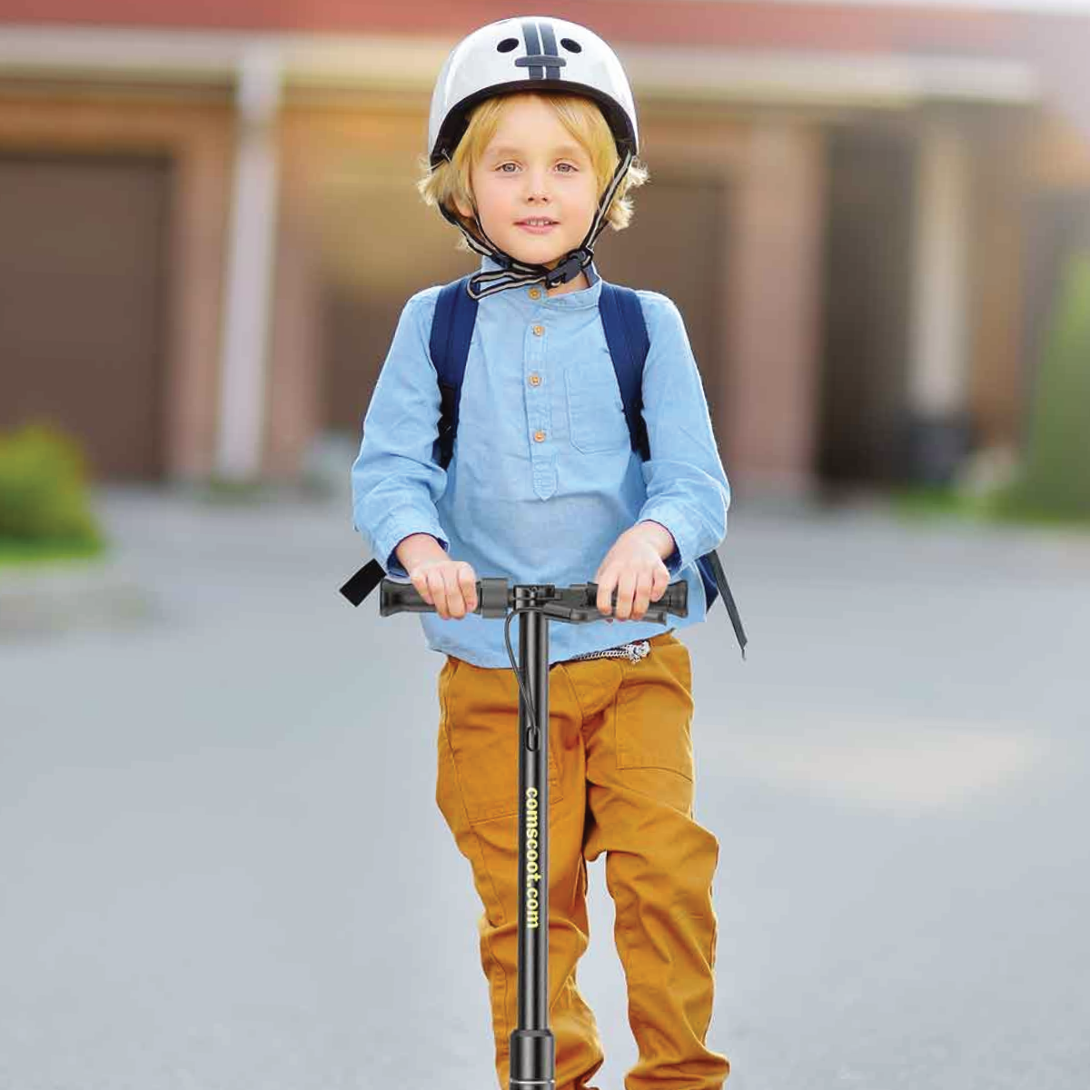 Ein Junge mit Helm, Rucksack fährt mit einem Roller auf der Straße.