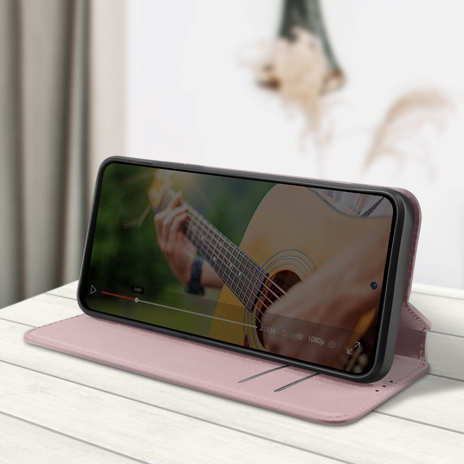 Telefono in custodia, riproduce video di un chitarrista, su un tavolo.