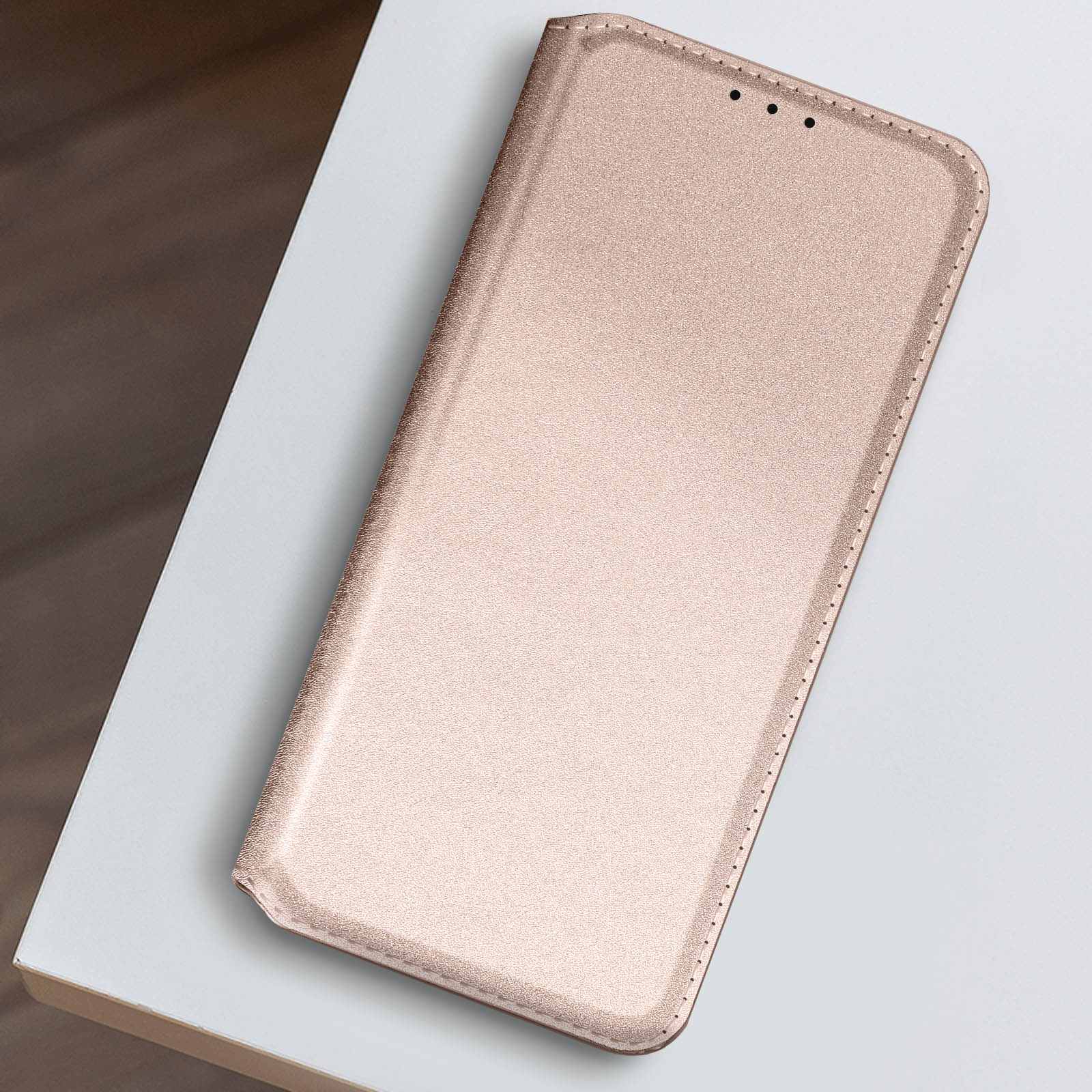 Una custodia per smartphone rosa chiusa su una superficie bianca.