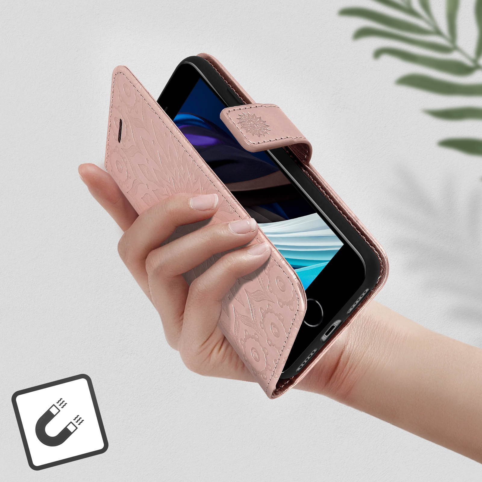 Una mano che tiene una custodia rosa con un design floreale, con un simbolo magnetico.